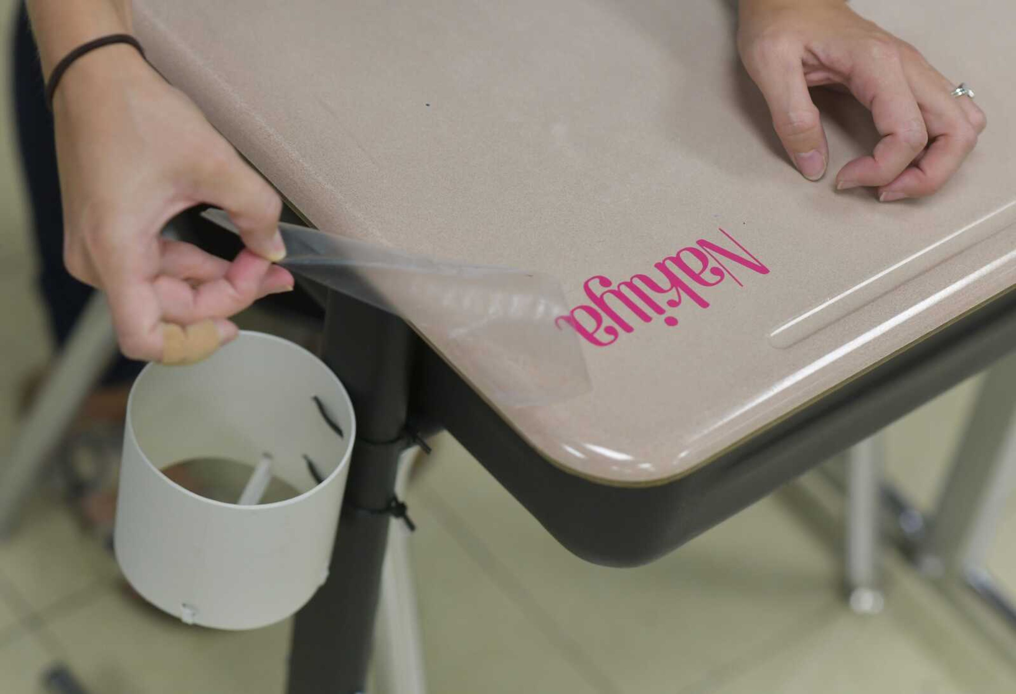 Fourth-grade teacher Allison Bradshaw decorates her students  desks with personalized vinyl lettering after designing a seating chart for her classroom Tuesday, Aug. 18, 2020, at Clippard Elementary in Cape Girardeau. During the upcoming semester, students cannot drink from communal water sources and volunteer-made water bottle holders have been attached to every desk in the school.