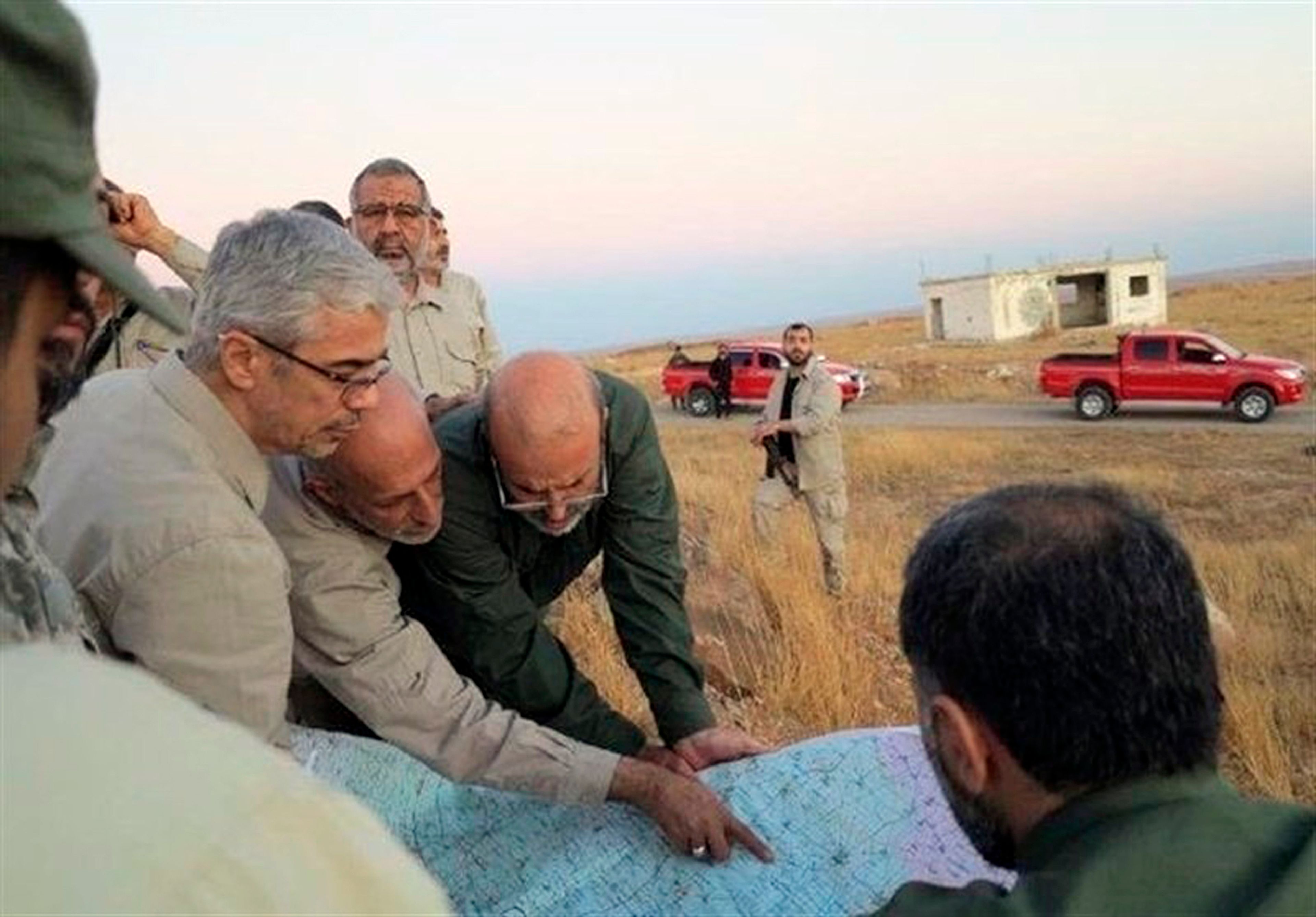 FILE - This file photo provided on Oct. 20, 2017 by the government-controlled Syrian Central Military Media, shows Iran's army chief of staff Maj. Gen. Mohammad Bagheri, left, looking at a map with senior officers from the Iranian military as they visit a front line in the northern province of Aleppo, Syria. (Syrian Central Military Media, via AP, File)