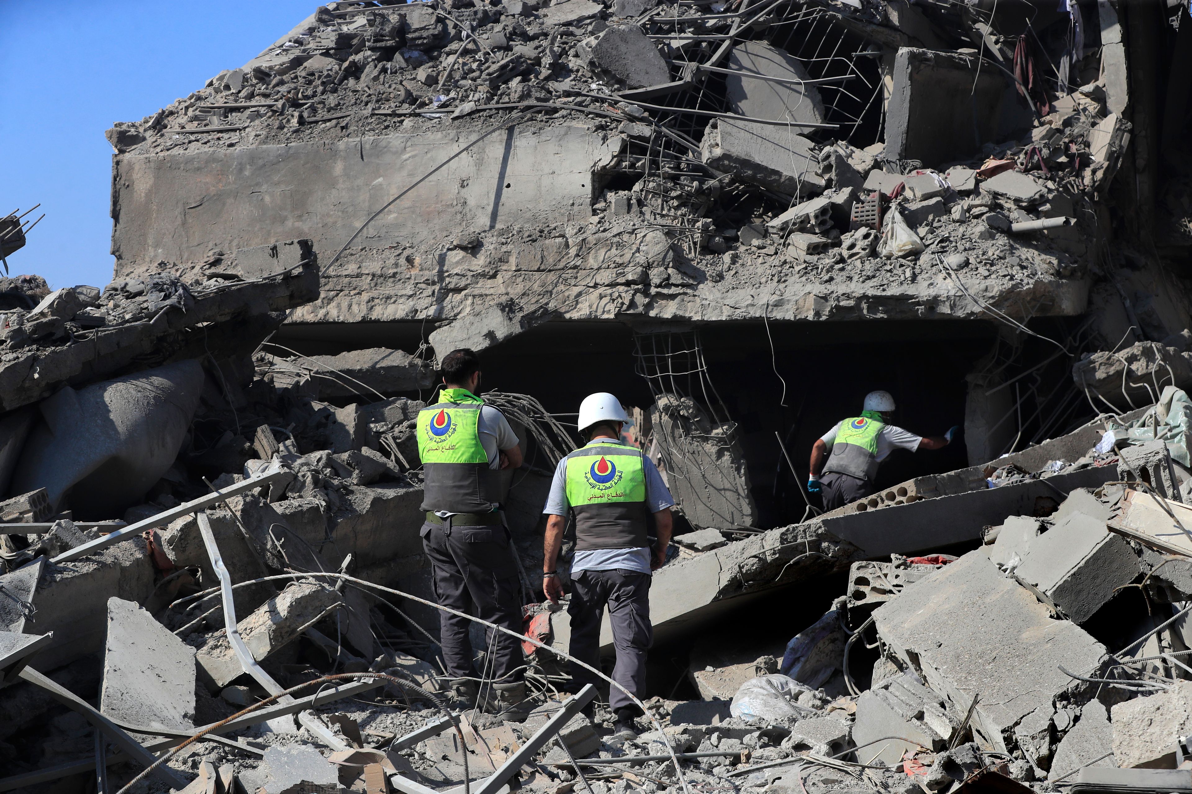 Hezbollah rescue workers search for victims on the rubble of destroyed buildings at commercial street that was hit Saturday night by Israeli airstrikes, in Nabatiyeh town, south Lebanon, Sunday, Oct. 13, 2024. (AP Photo/Mohammed Zaatari)