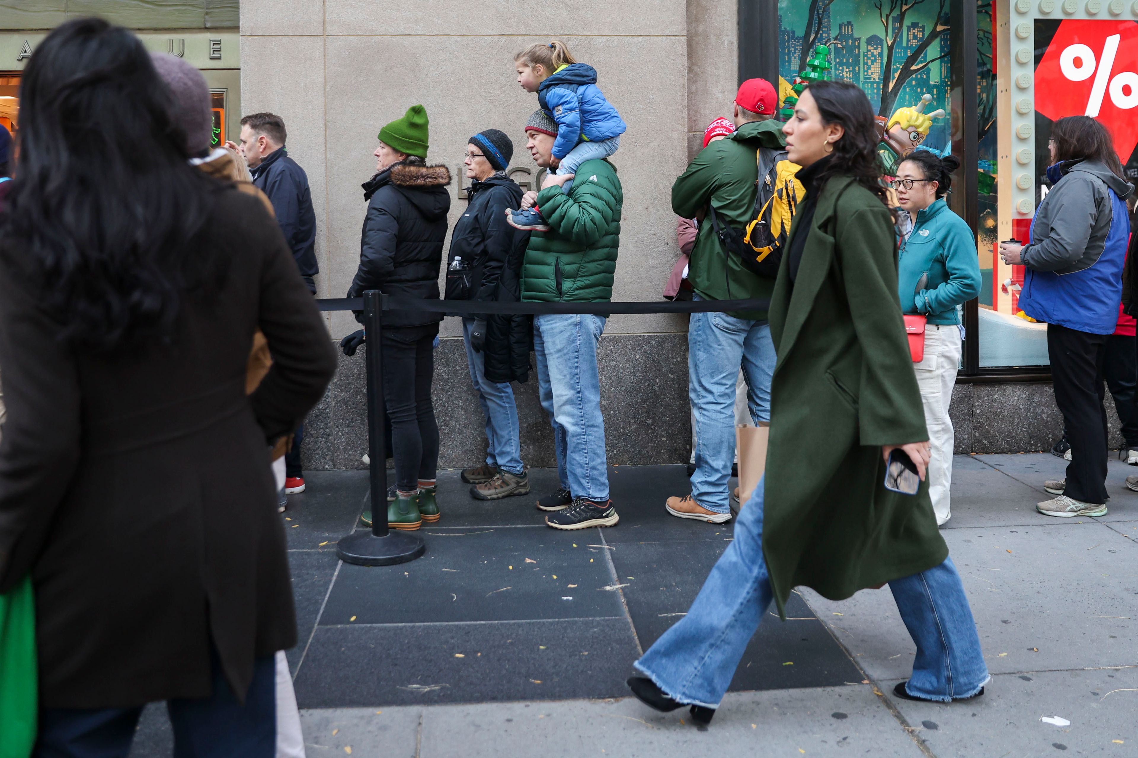 A long line of people wait to enter the Lego store while shoppers walk by, Friday, Nov. 29, 2024, in New York. (AP Photo/Heather Khalifa)