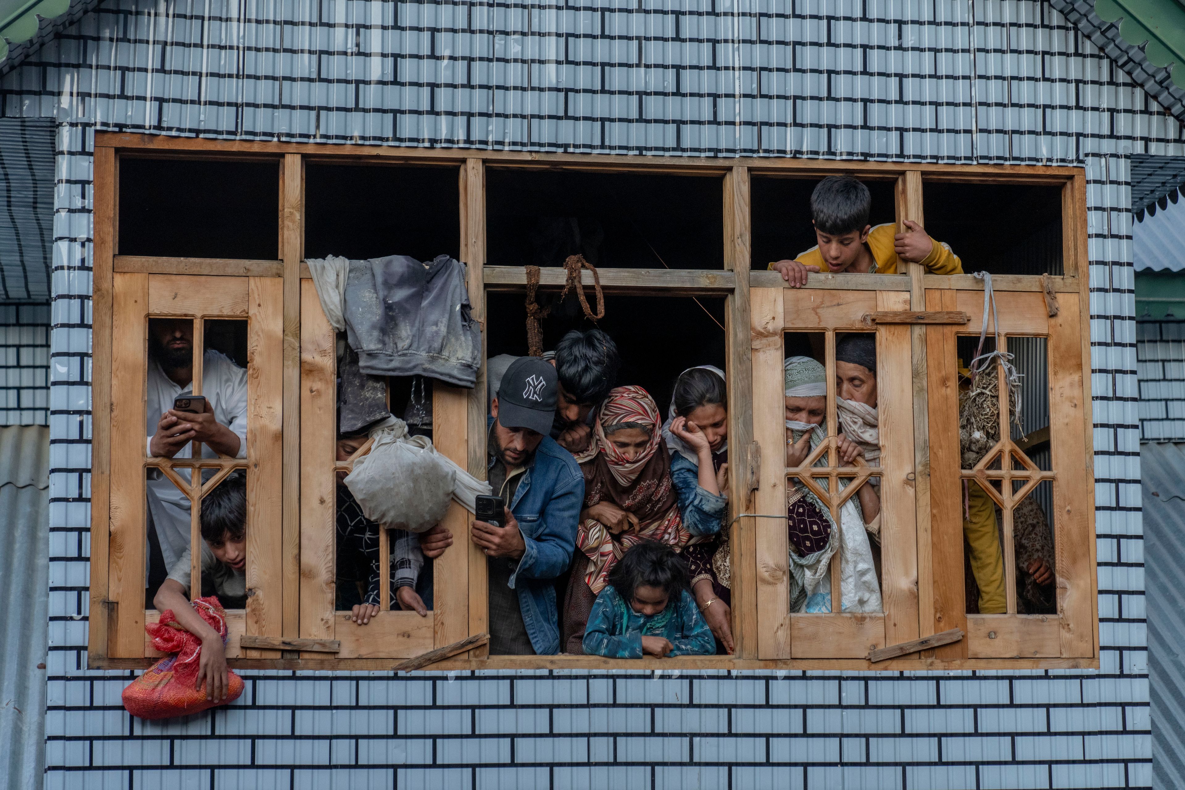 Kashmiri villagers watch from the window of a residential house the funeral of Mushtaq Ahmad, an army porter who was among those killed in a rebel ambush on an army vehicle on Thursday night, in Nowshera village north of Srinagar, Indian controlled Kashmir, Friday, Oct. 25, 2024. (AP Photo/Dar Yasin)