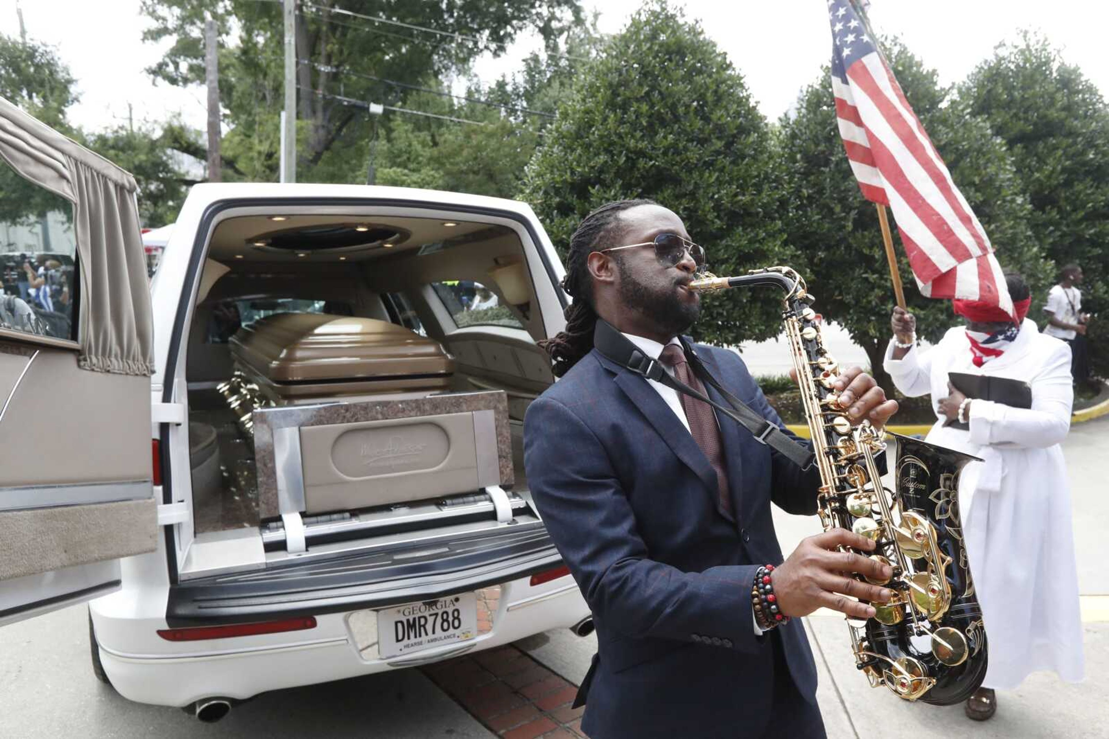 A musician plays music near the hearse carying the casket of Rayshard Brooks on Tuesday in Atlanta. Brooks died after being fatally shot by an Atlanta police officer.