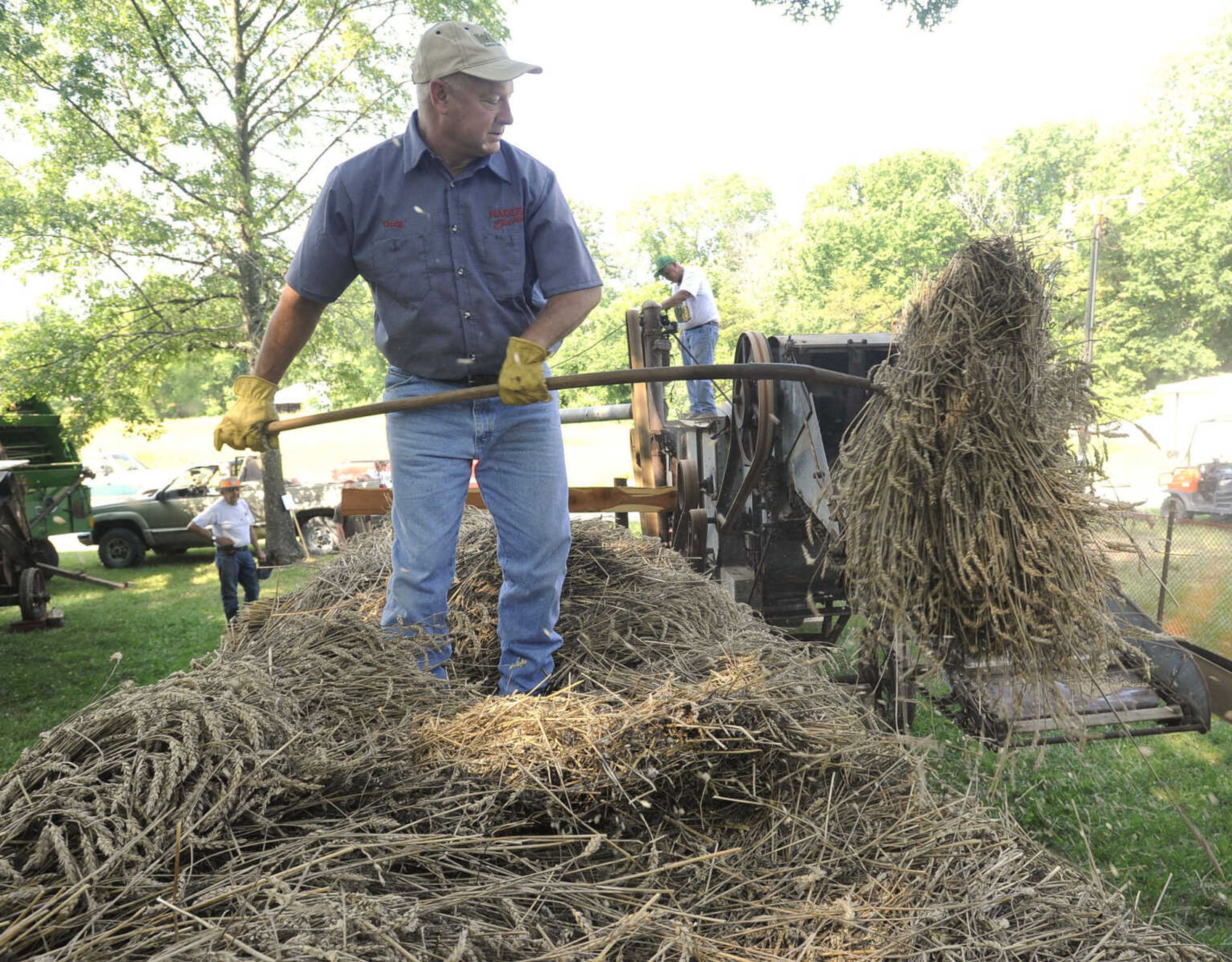 Greg Hadler demonstrates wheat threshing with his father, Willard Hadler, Saturday at Old Timers' Day in Perryville, Mo.