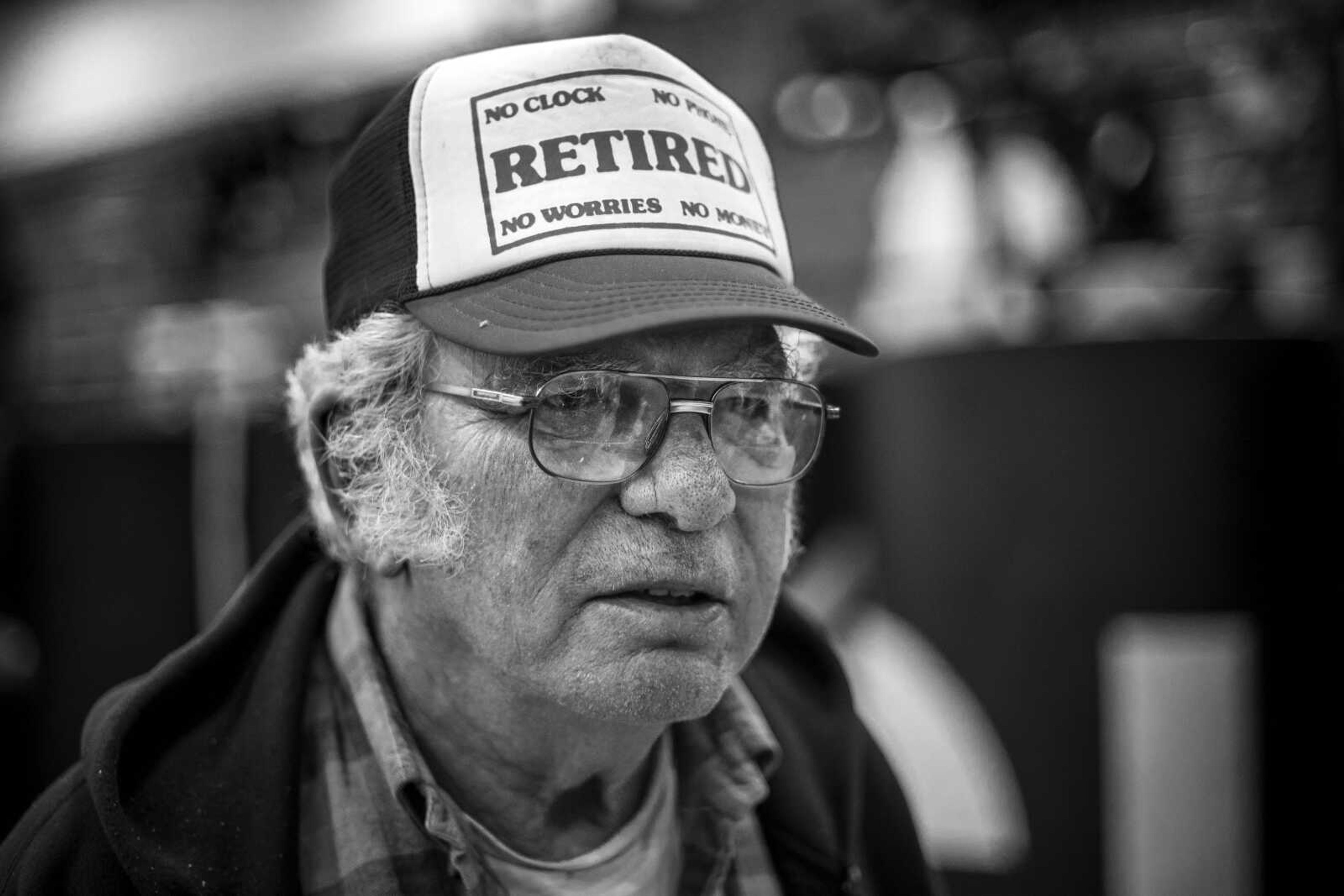 John W. Amelunke, 71, poses for a portrait in his cap which reads, "RETIRED; no clock, no phone, no worries, no money," at Cape Central Junior High Saturday, Dec.15, 2018. "But I'll tell you what, don't ever retire," he said. "Now I work more than ever."