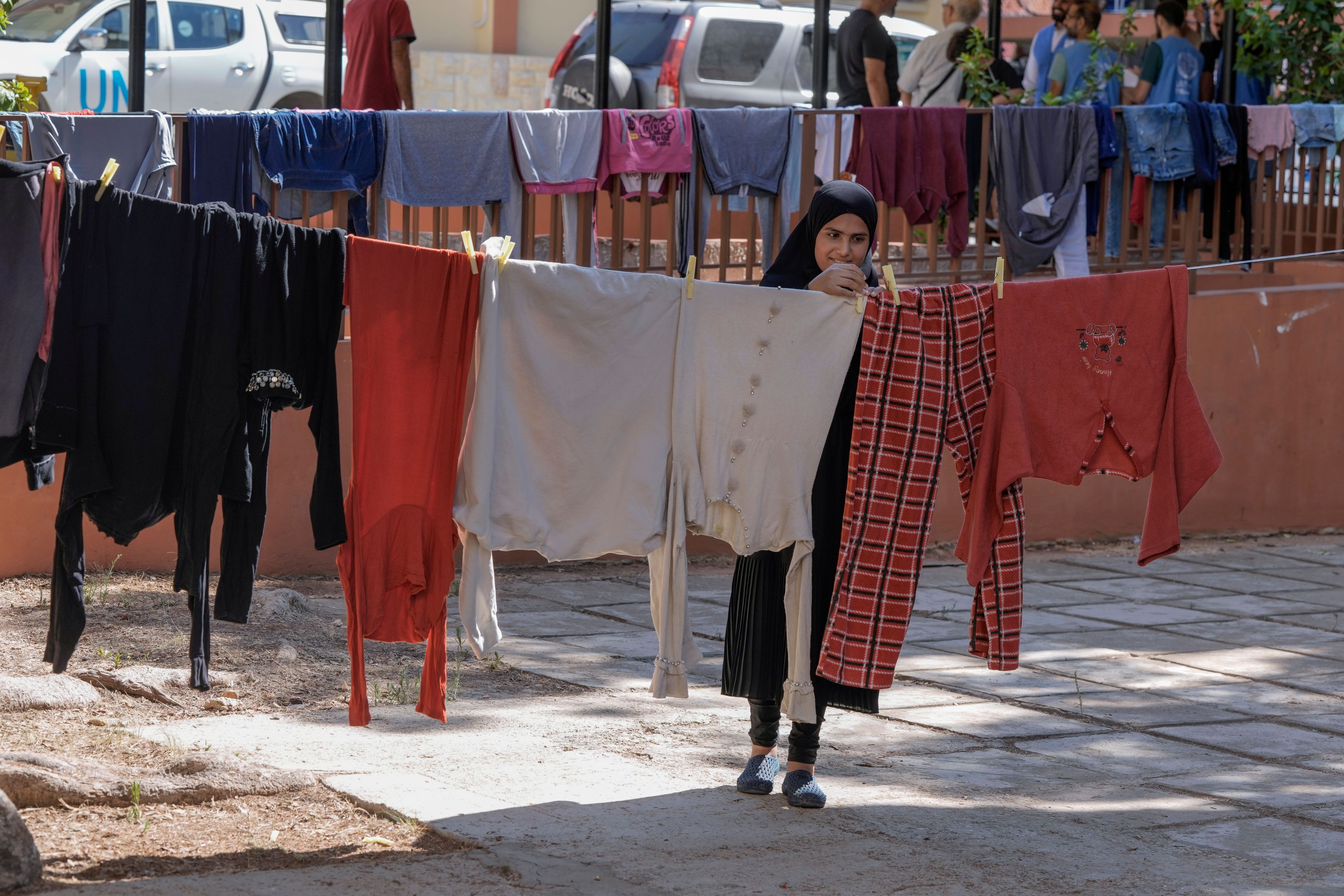 Turkeya Mohammed hangs her family's laundry at a vocational training center run by the U.N. agency for Palestinian refugees, or UNRWA, in the southern town of Sebline, south of Beirut, Lebanon, Friday, Oct. 4, 2024, after fleeing the Israeli airstrikes in the south. (AP Photo/Bilal Hussein)