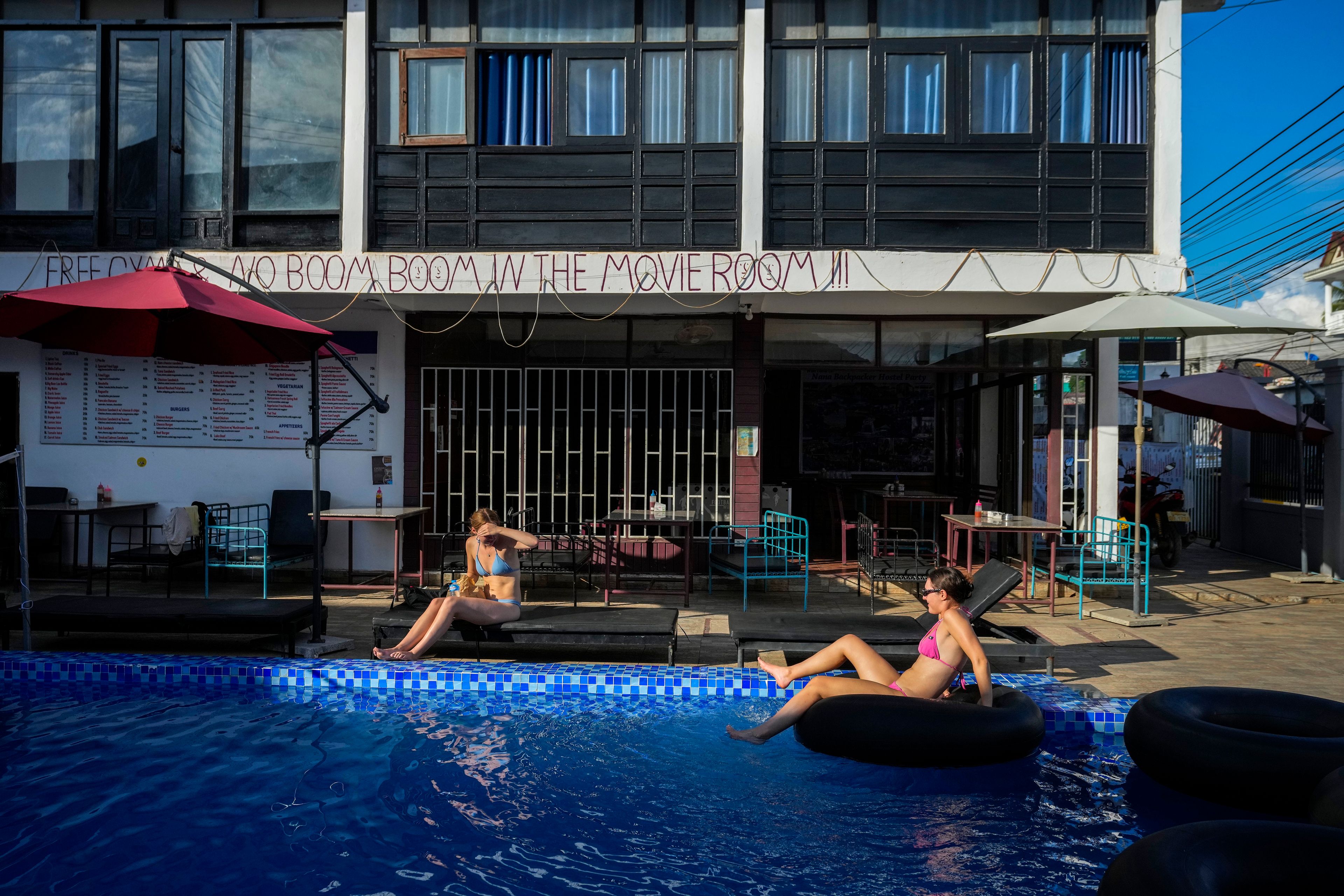 Foreign tourists relax at a swimming pool at Nana Backpack hostel in Vang Vieng, Laos, Tuesday, Nov. 19, 2024. (AP Photo/Anupam Nath)