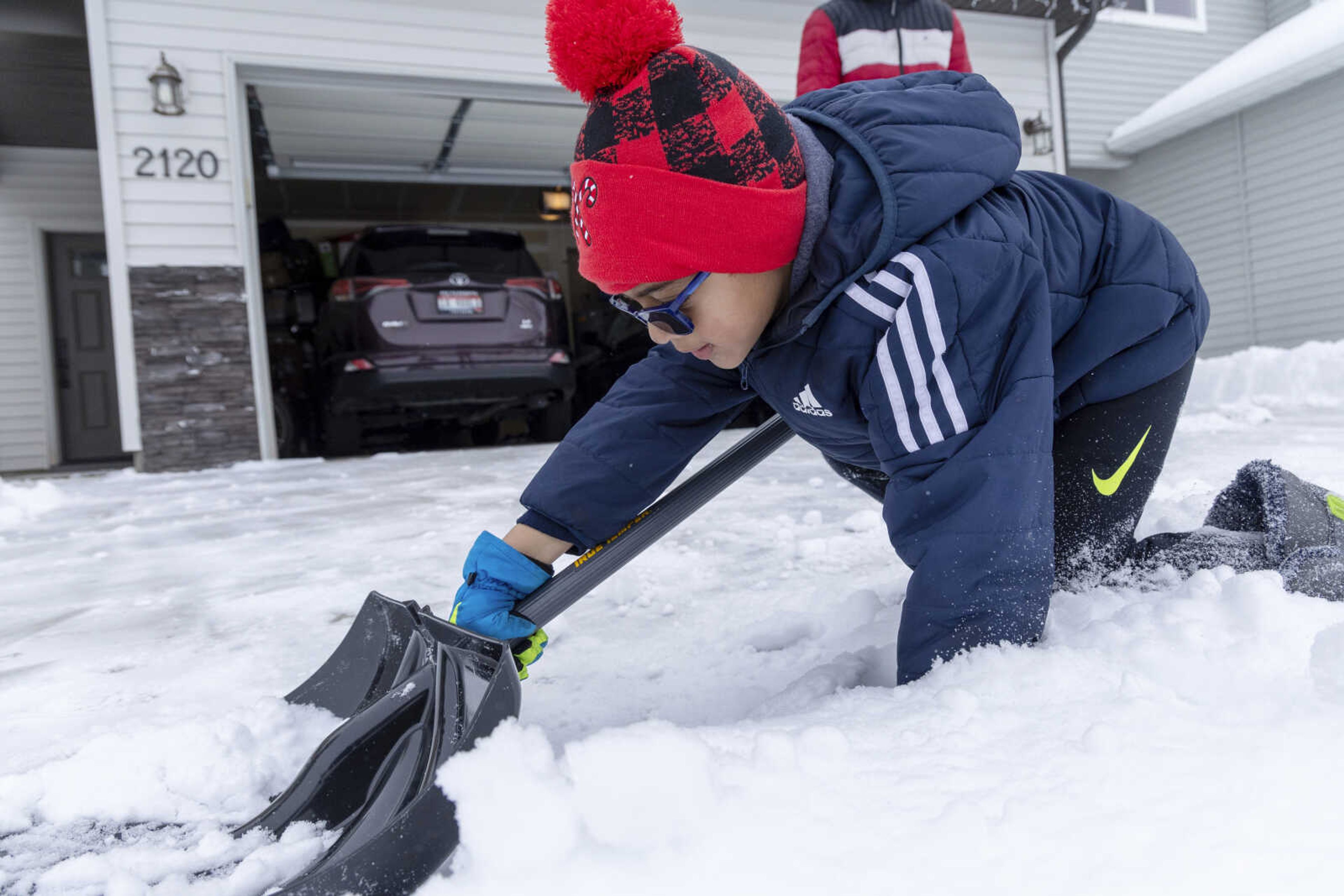 Adyaan Islam, 5, helps his family shovel the driveway Sunday in Meridian, Idaho.