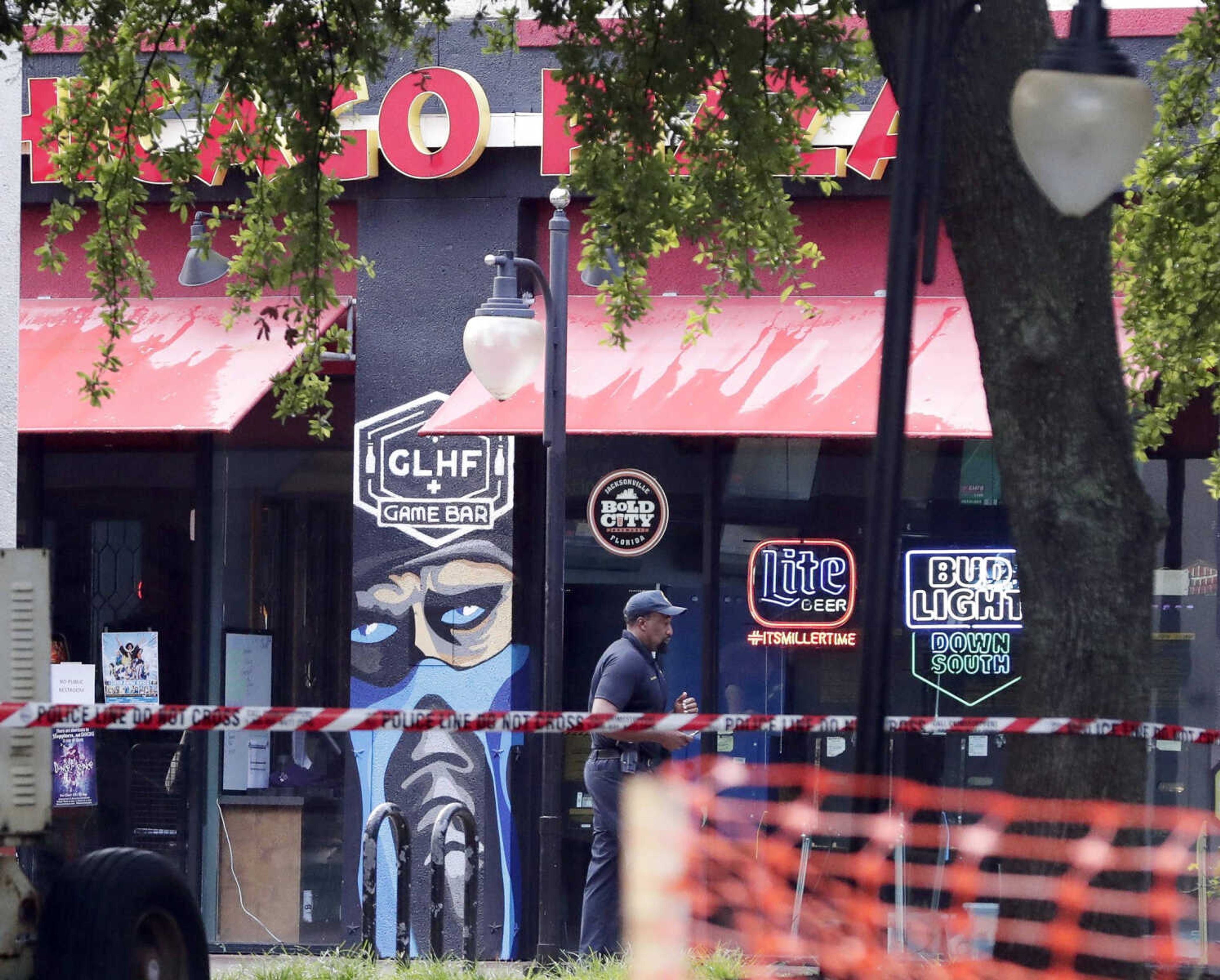 A police officer walks by the front of a Chicago Pizza and GLHF Game Bar on Monday at the scene of fatal shooting Sunday at The Jacksonville Landing in Jacksonville, Florida.