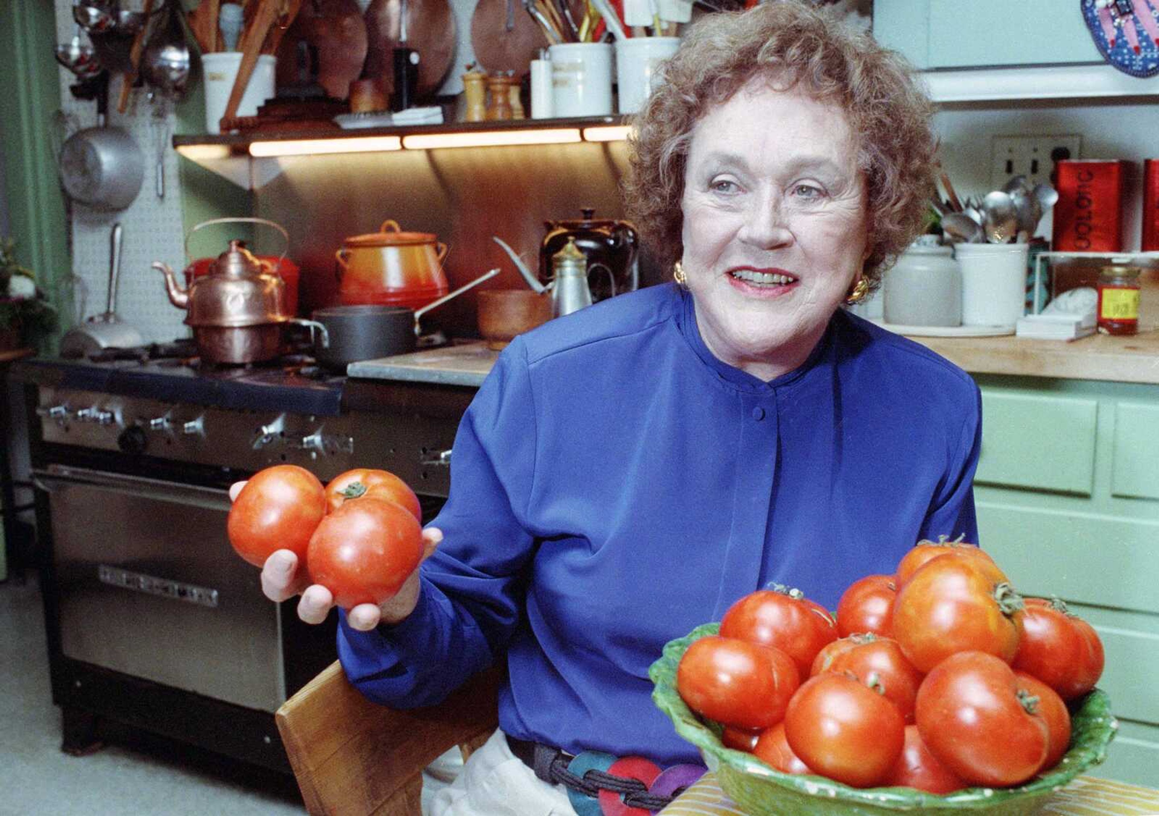 Julia Child shows off tomatoes Aug. 13, 1992, in the kitchen at her home in Cambridge, Mass. More so than the tools and techniques she popularized, Child's most lasting legacy may be her spirit and sense of humor. That was the conclusion of several chefs and food magazine editors asked to describe Child's contributions to American home cooking as a new movie about her life is about to open. (Associated Press file)