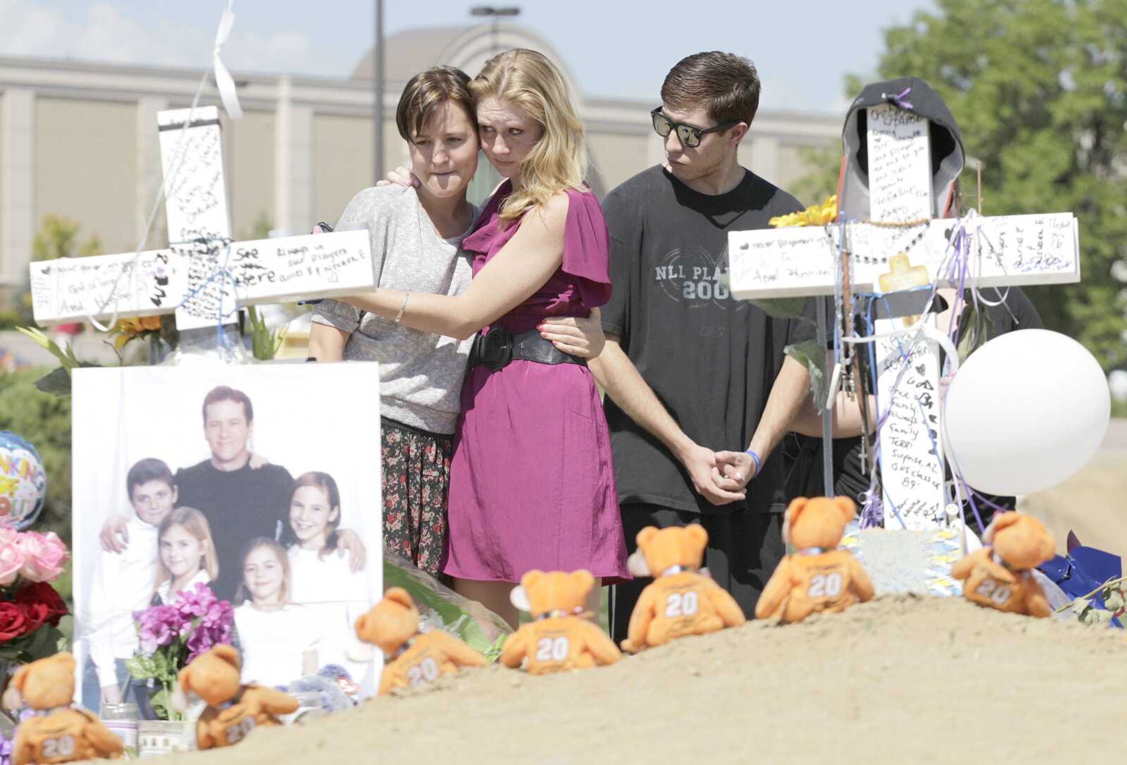 From left, Ashley Deuell, 18, Samantha Winslow, 18, and Michael Espinosa, 20, cry Tuesday as they view crosses dedicated to Gordon Cowden, on the left, and Alex &#8220;AJ&#8221; Boik at a growing memorial to the victims of Friday&#8217;s mass shooting in a movie theater in Aurora, Colo. (Ted S. Warren ~ Associated Press)