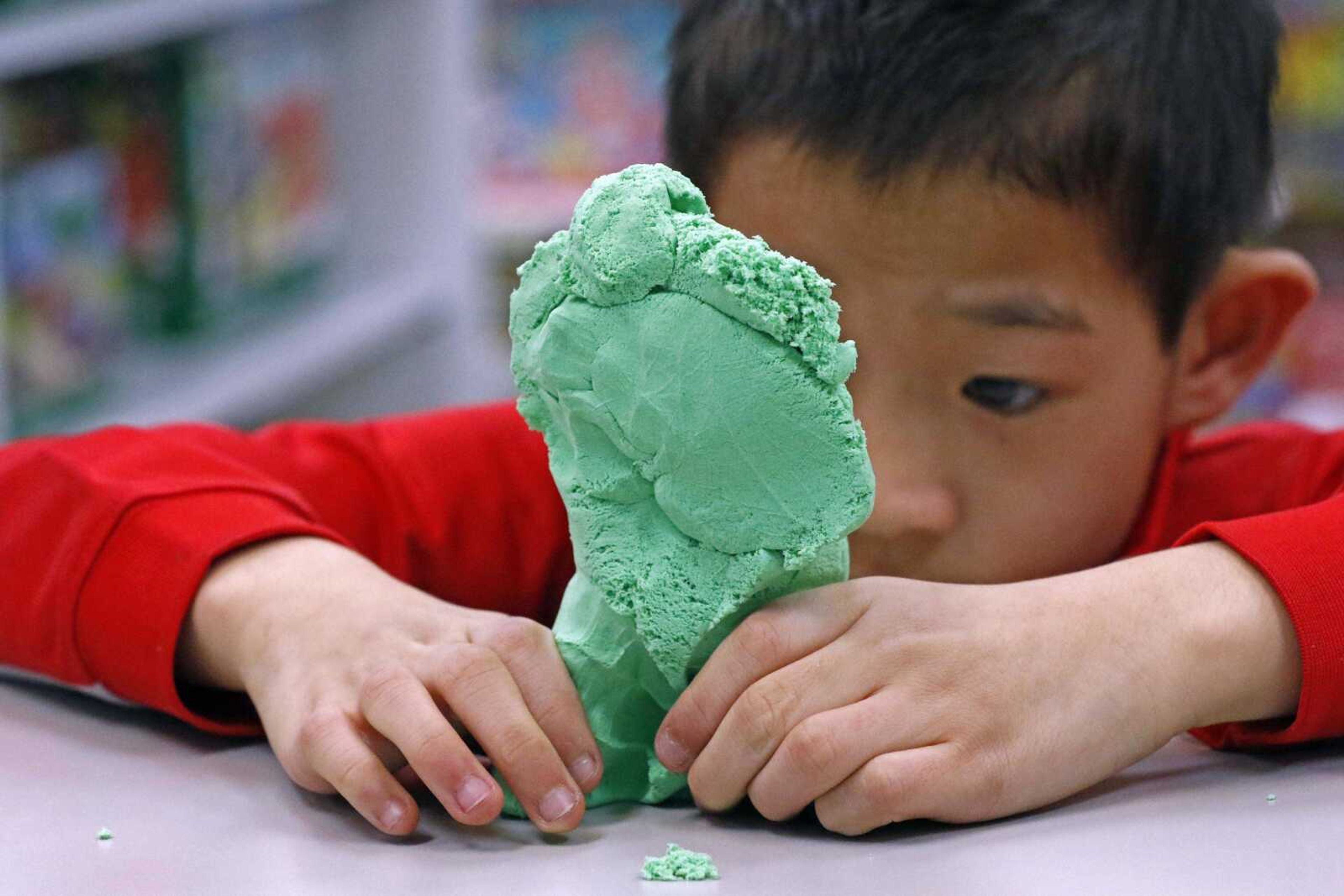 Paxton Mathis, 8, plays with a bright-colored molding clay Dec. 13 at Time 4 Toys in Flowood, Mississippi. The youngest child of store owner Bethany Mathis, Paxton, who has sensory processing disorder, often tests out some of the multipurpose toys offered in his mother's toy store.