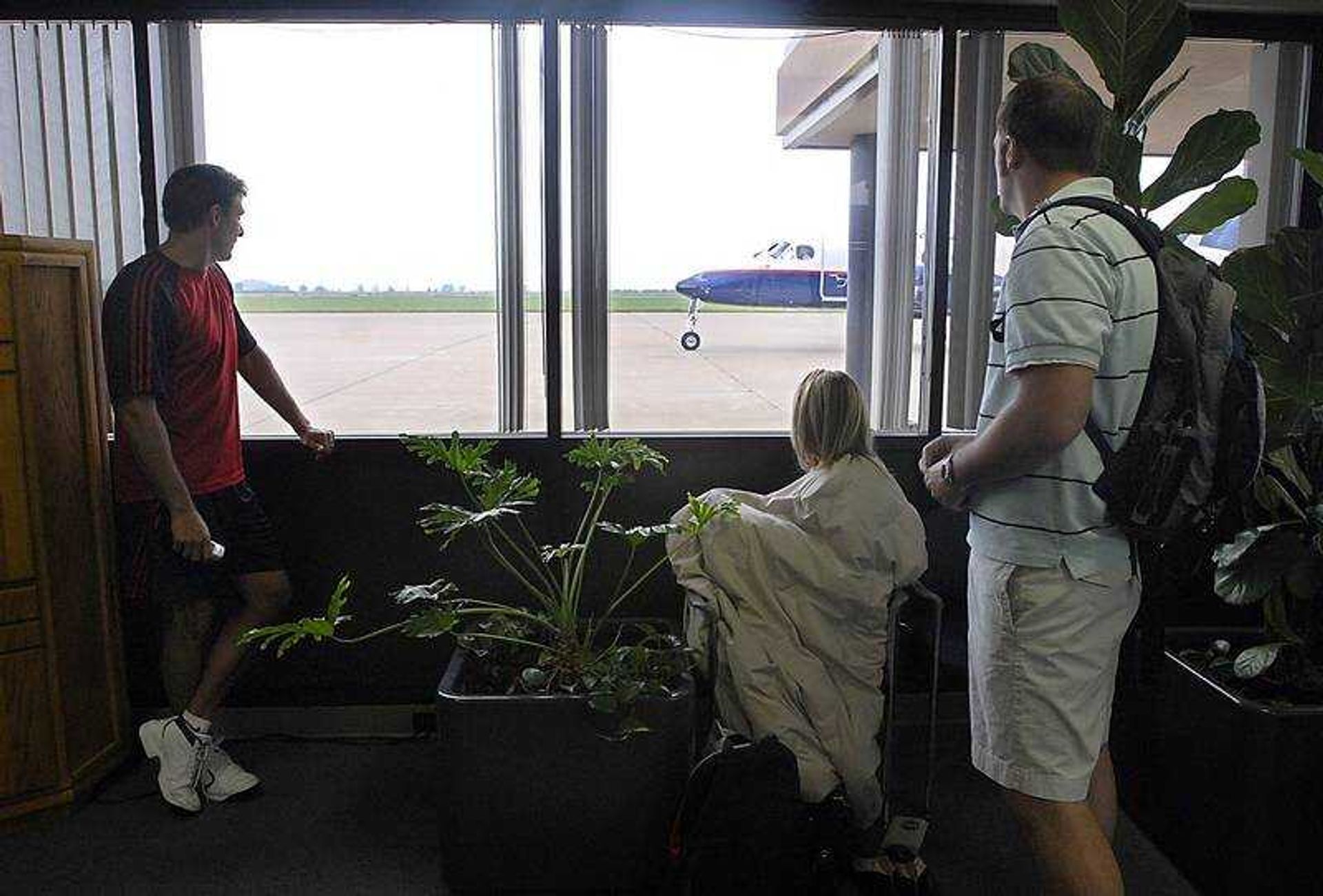 KIT DOYLE ~ kdoyle@semissourian.com
American Connection passengers Greg Bayus, left, Kim Houghtaling and Lee Currault watched a grounded Great Lakes flight Friday morning at the Cape Girardeau Regional Airport. Their flight made an emergency landing due to a broken windshield, and the Great Lakes flight came back to Cape Girardeau several minutes after departure due to vapor in the cabin.