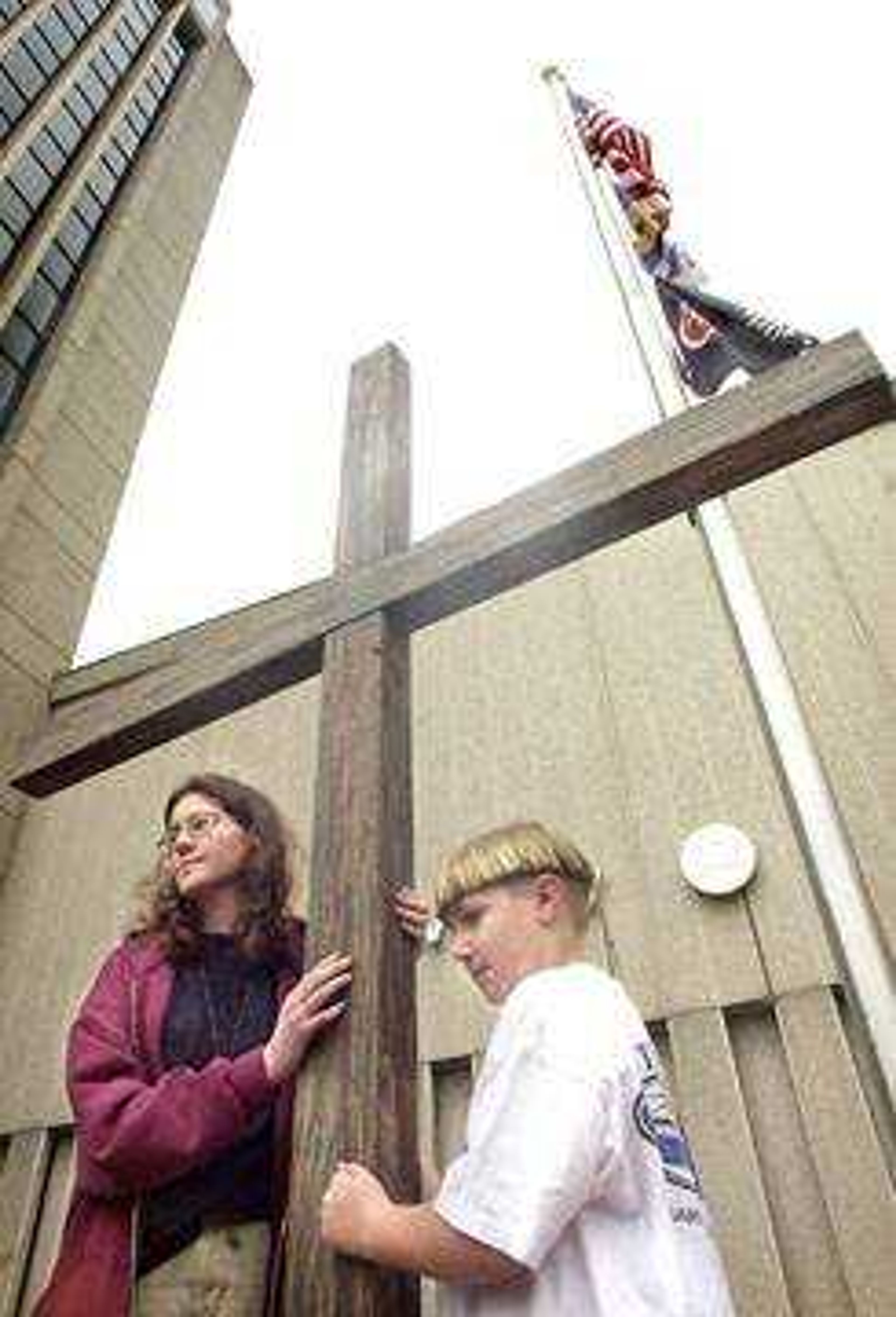 Pam Acker, left, and Steven Watkins displayed a wooden cross in front of the KFVS-TV building on Broadway in Cape Girardeau, the sixth stop on the Way of the Cross walk on Friday.