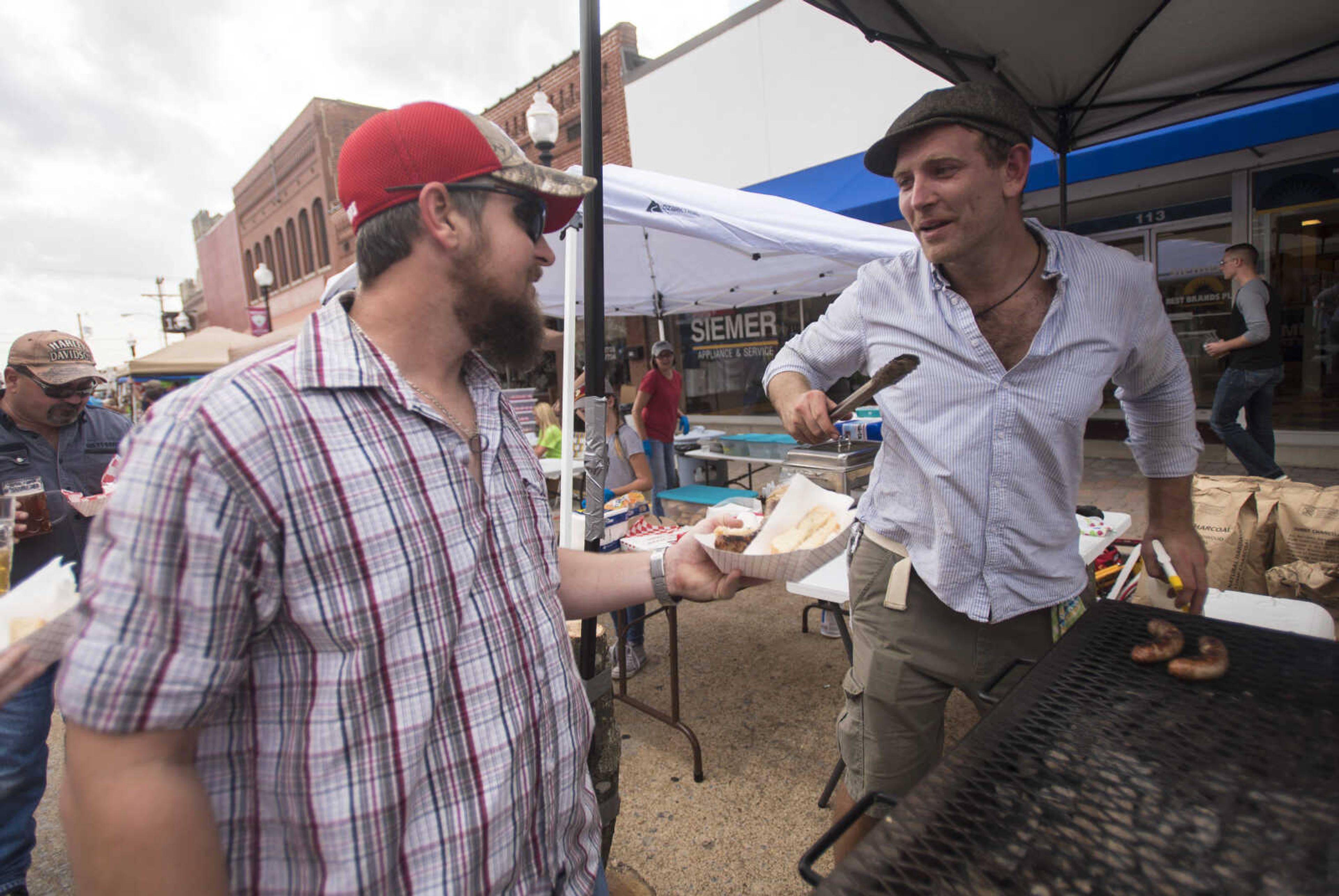 Dustin Wildhaber, left, waits in line for a german bratwurst from Christian Voigt at the Uptown Jackson Oktoberfest, Saturday, October 7, 2017.