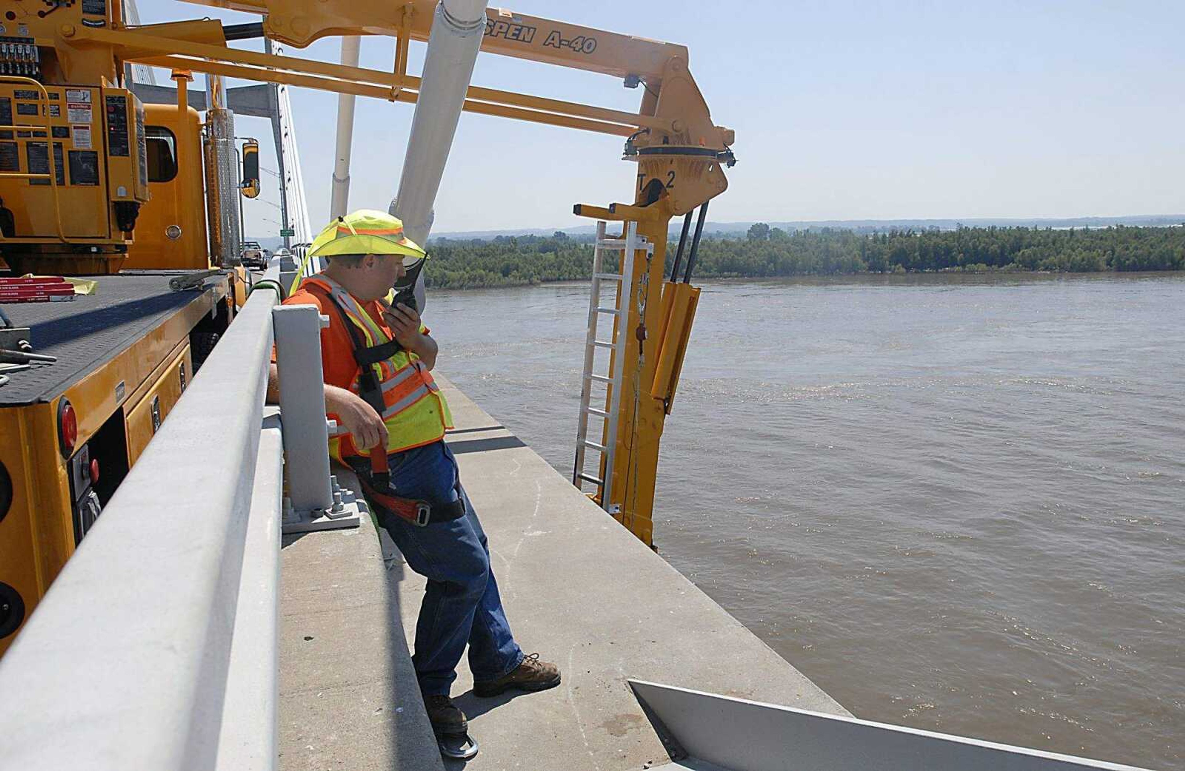 KIT DOYLE ~ kdoyle@semissourian.com
Jason Owens, with Cotner Electric Co., spoke with others working under the Emerson Bridge on a boom from the truck to the left on Thursday, July 17, 2008, as MoDot crews and contractors sections of conduit.