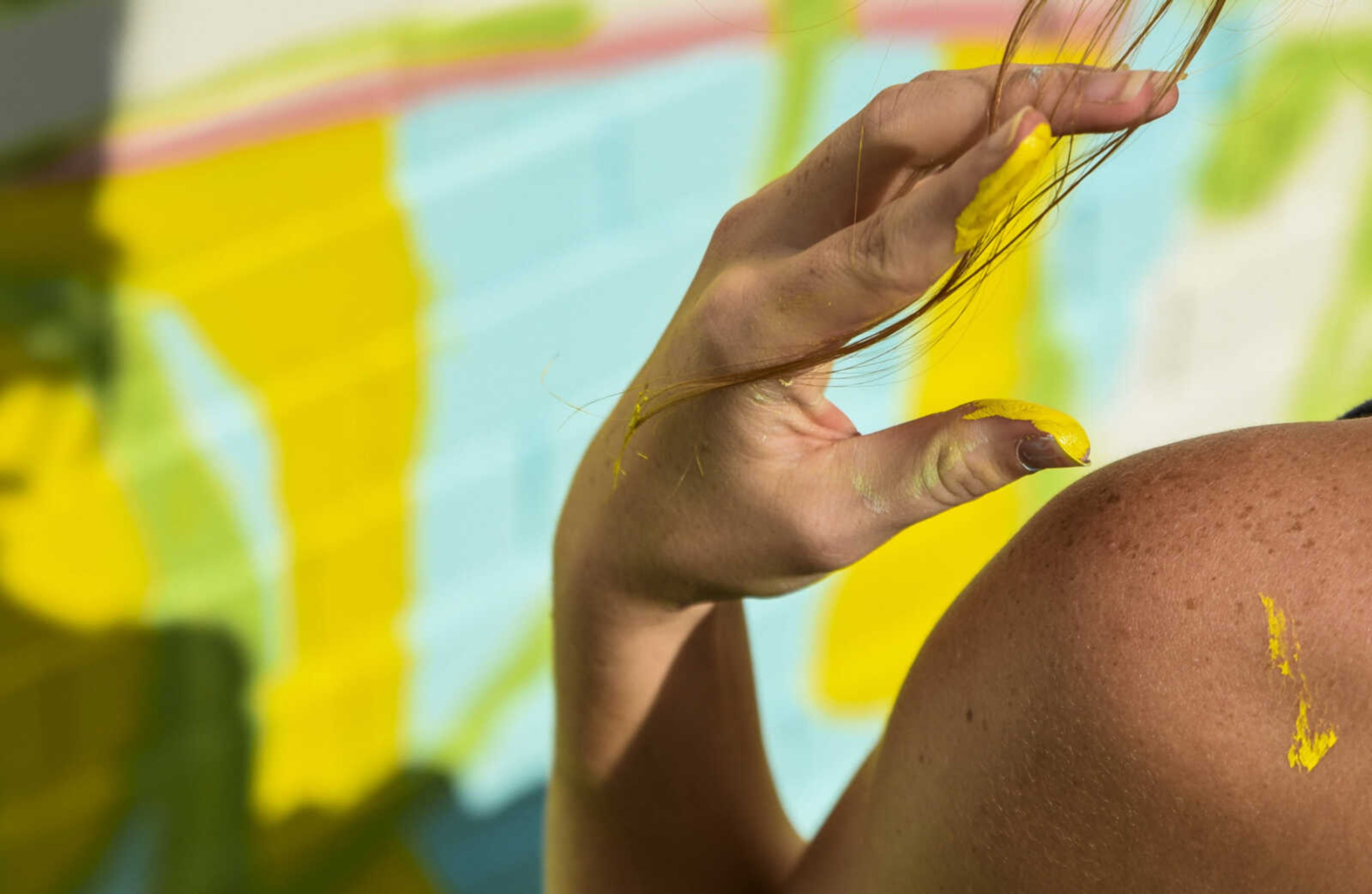 Maggie Shelton wipes a strand of hair out of her face while working on the mural on the side of the One City building Wednesday, July 18, 2018 in Cape Girardeau.