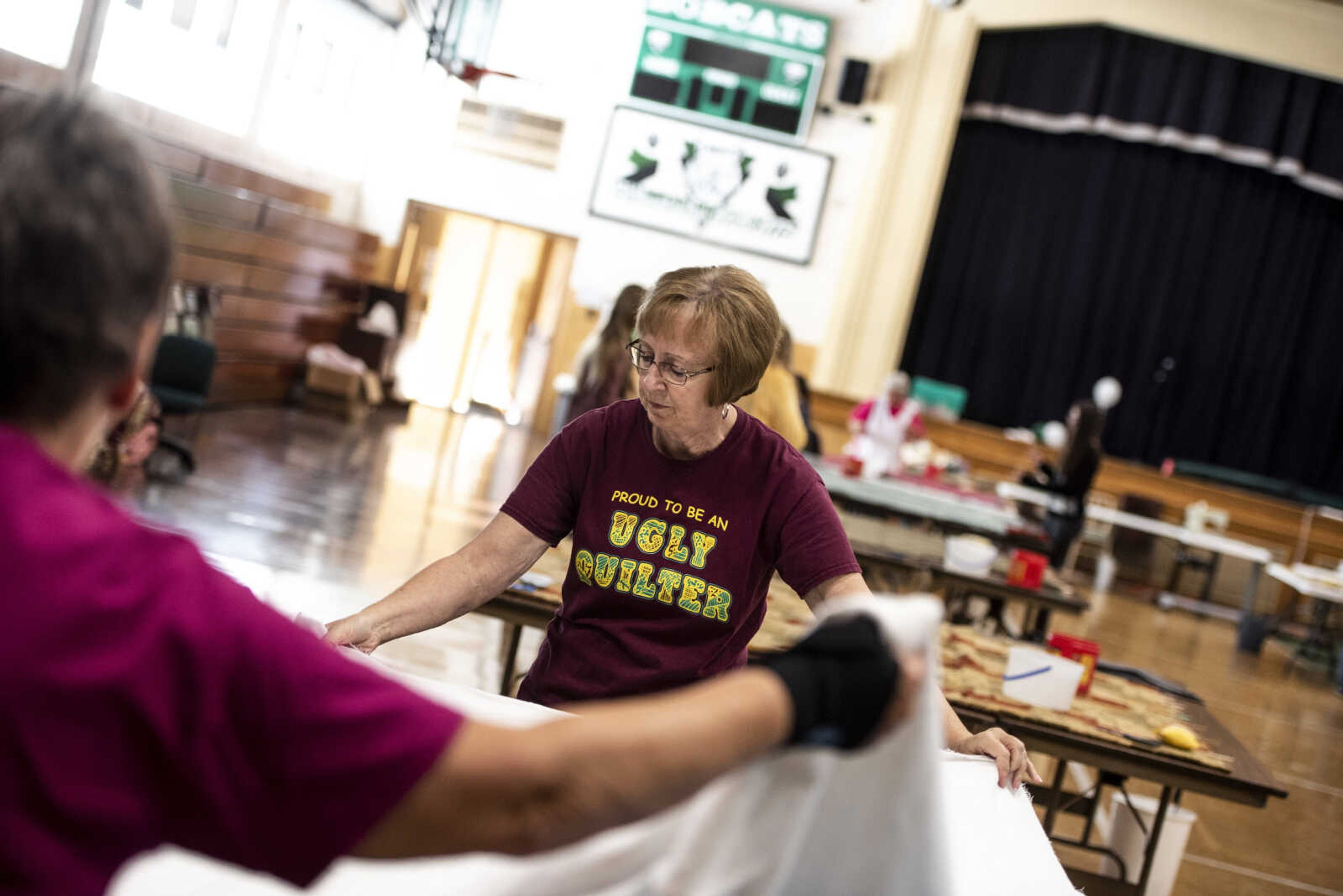 Linda Shaffar, back, helps Carol Glueck, front, unfold fabric to put the middle blankets into the bed roll before it's tacked together during the Ugly Quilt Weekend at St. Vincent de Paul Parish Sunday, Oct. 28, 2018, in Cape Girardeau.