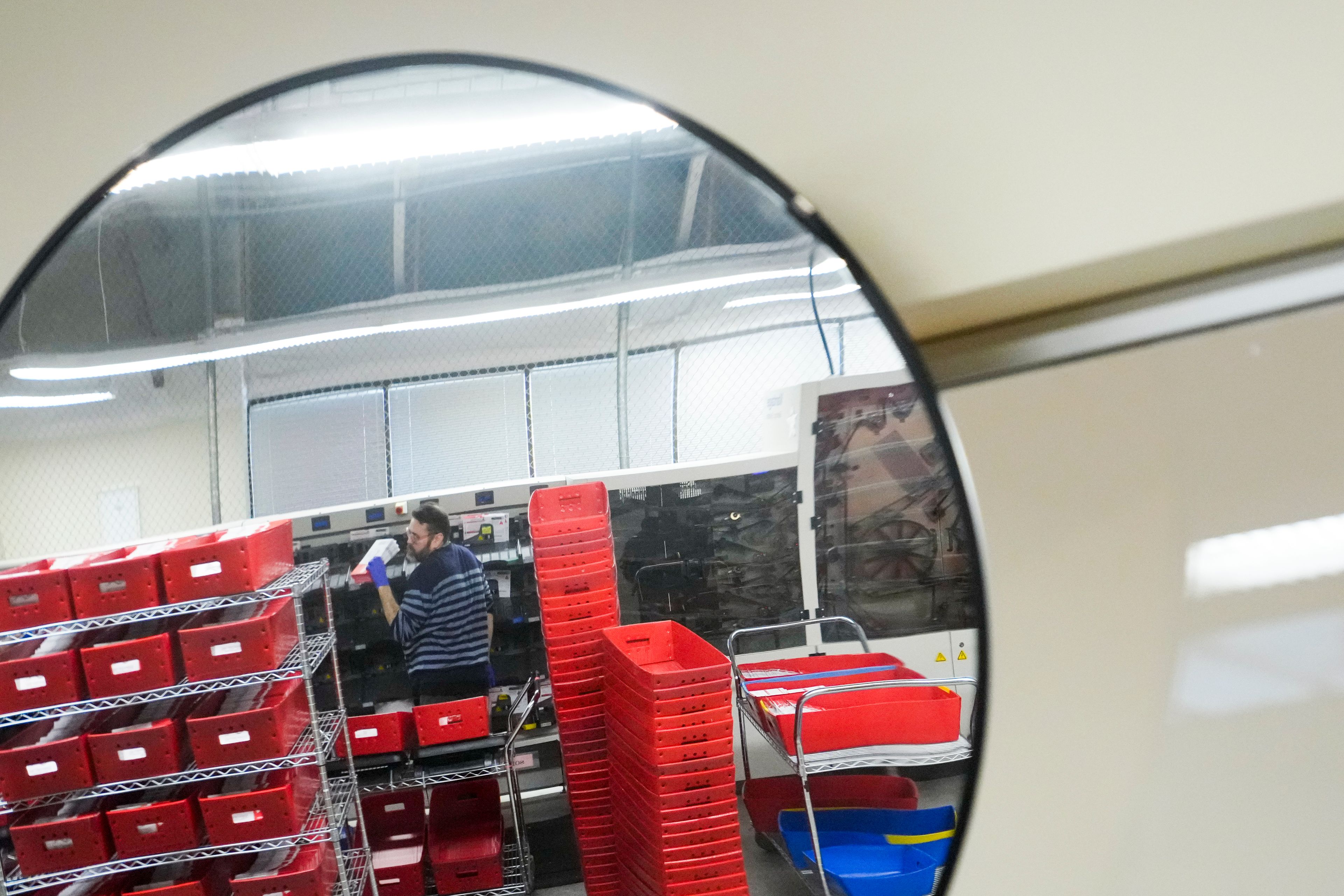 A worker moves sorted ballots into trays, as reflected in a mirror, at the King County Elections headquarters on Election Day, Tuesday, Nov. 5, 2024, in Renton, Wash. (AP Photo/Lindsey Wasson)