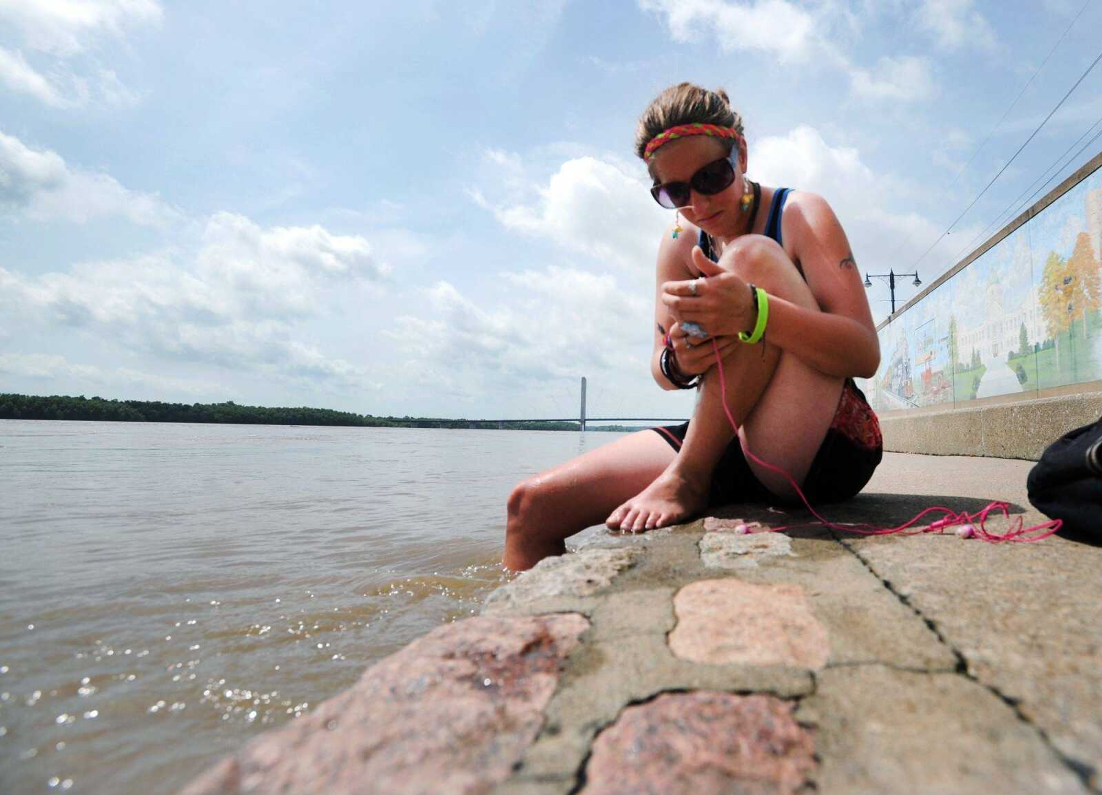 Marissa Giammanco flips through her playlist while dipping her leg in the Mississippi River on Wednesday morning in downtown Cape Girardeau. "It's pretty cold," Giammanco said of the water. The Themis Street flood gate was closed by the city Wednesday afternoon as the river continues to rise above flood stage. Flood stage is 32 feet, and the river is forecast to rise past 43 feet by early next week. (Laura Simon)