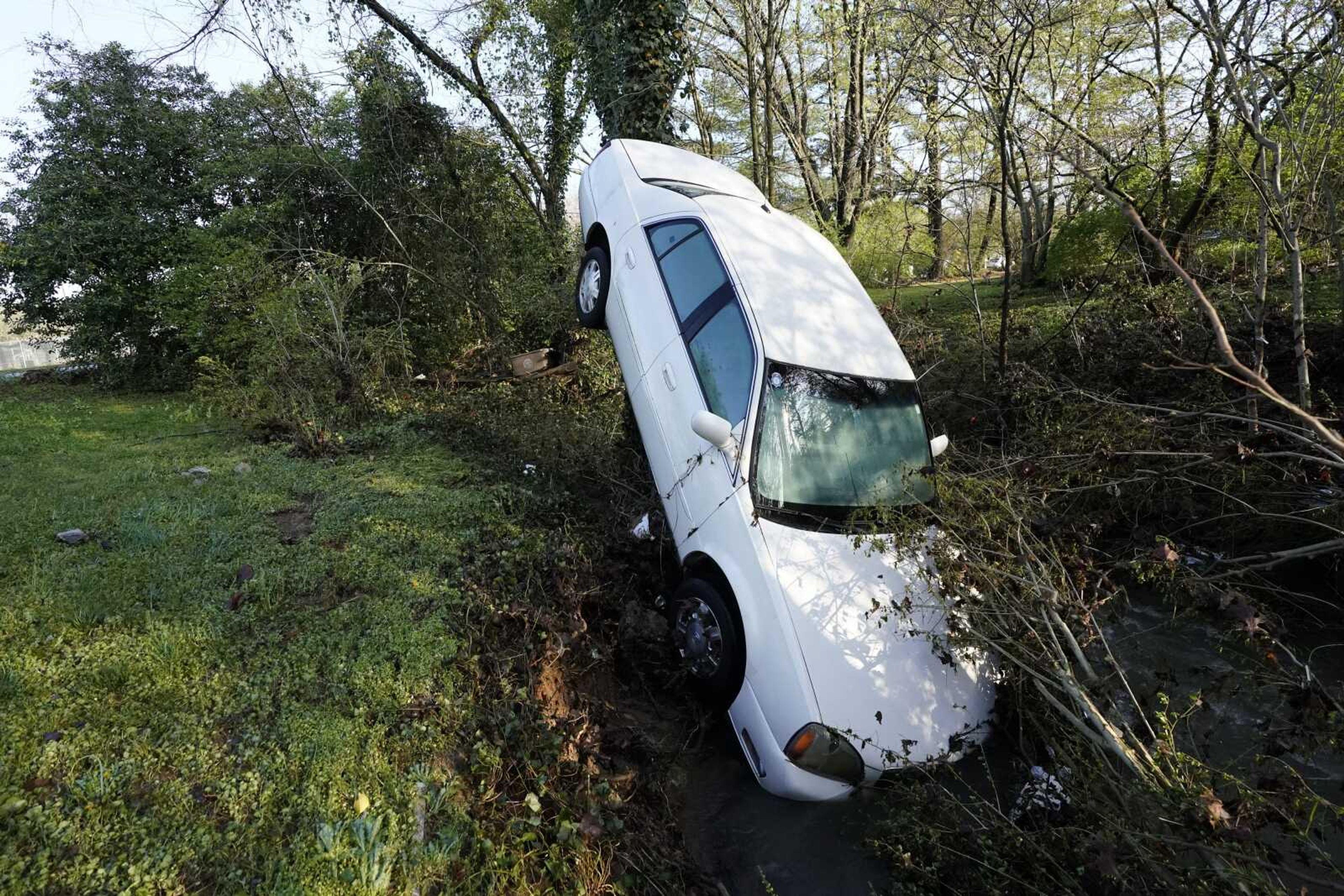 A car that was carried by floodwaters leans against a tree in a creek Sunday in Nashville, Tennessee. Heavy rain across Tennessee flooded homes and roads as a line of severe storms crossed the state.