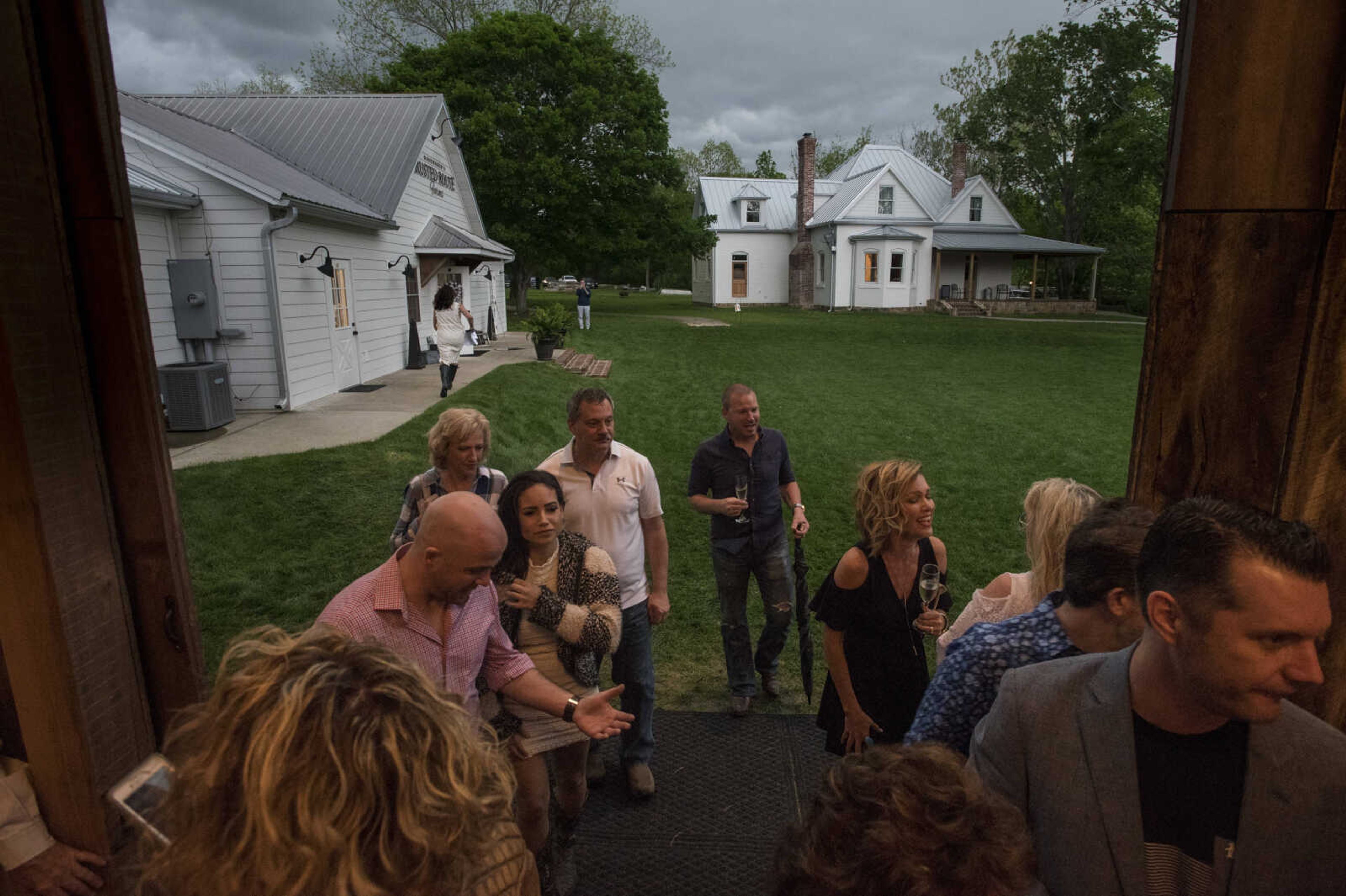 Guests flee into the barn at Rusted Route Farms as a thunderstorm approaches on April 29, 2017 during a Swine & Dine pig roast benefiting The Tailor Institute.