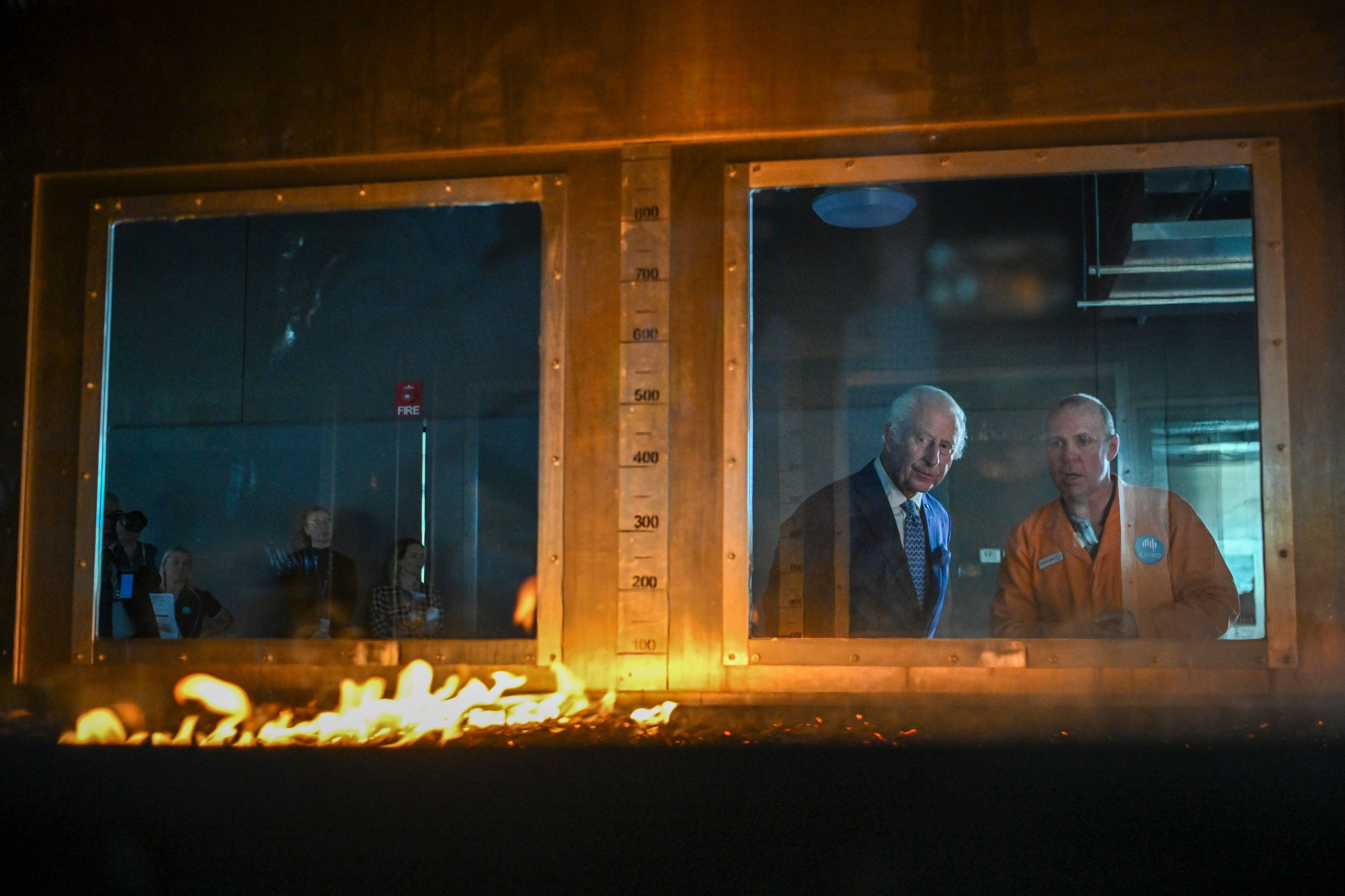 Britain's King Charles III listens to research scientist Dr. Matt Plucinski, right, describe the "Pyrotron" combustion wind tunnel during a visit to the CSIRO National Bushfire Behaviour Research Laboratory in Canberra, Monday, Oct. 21, 2024. (AP Photo/Tracey Nearmy, Pool)