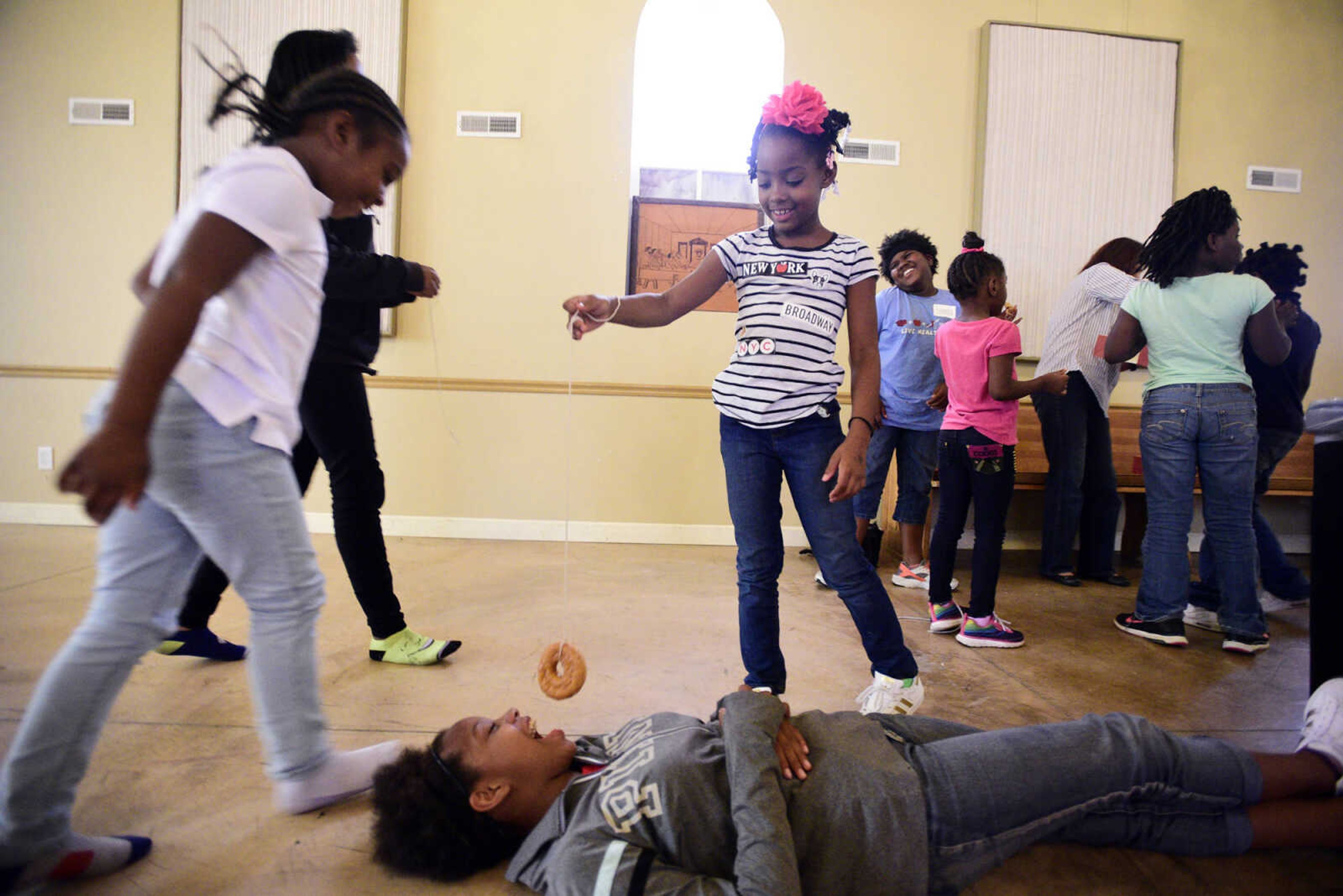 Kamajah Hamilton dangles a donut above Kaylin Maney on Monday, Aug. 14, 2017, during the Salvation Army's after school program at The Bridge Outreach Center in Cape Girardeau.