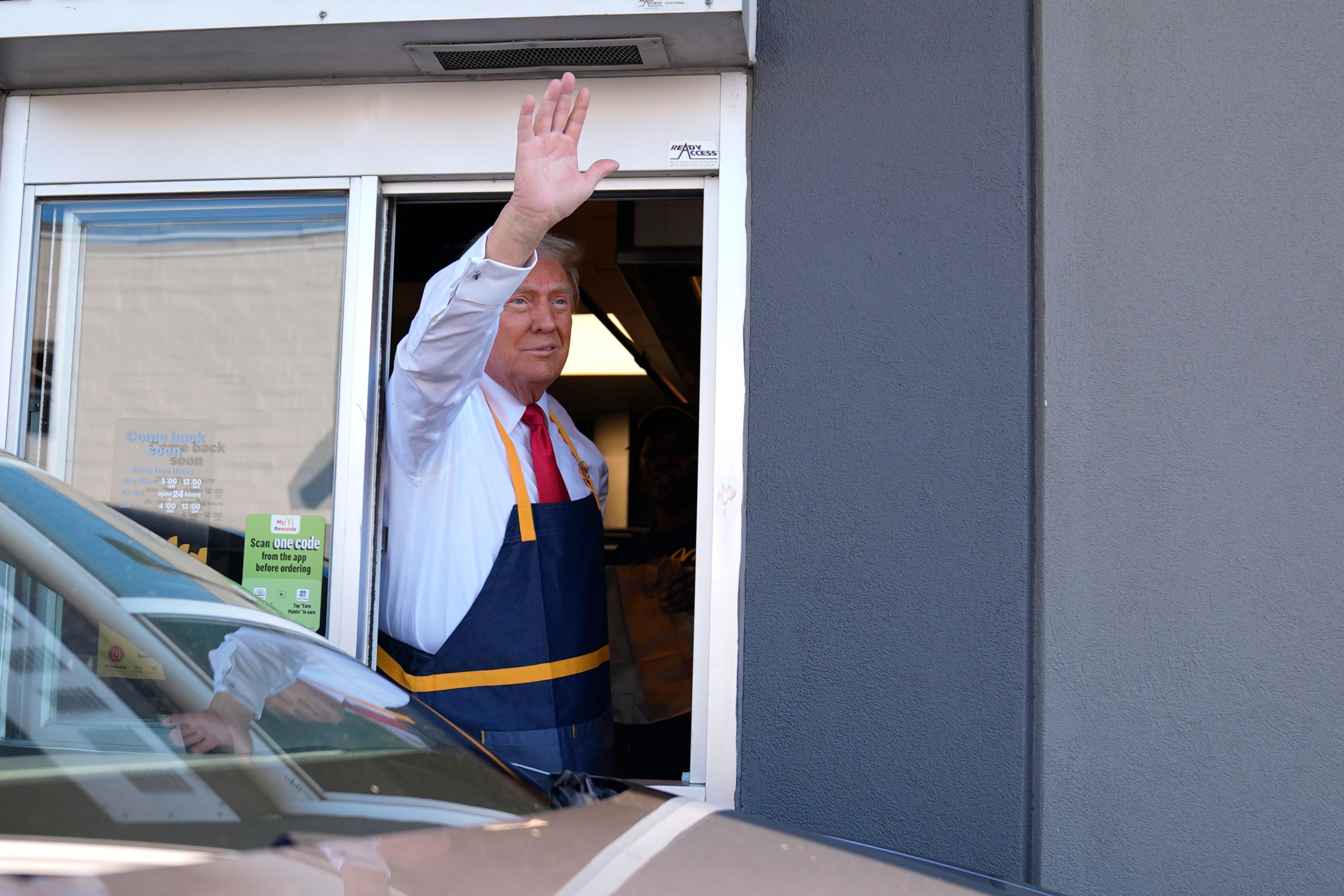 Republican presidential nominee former President Donald Trump waves from a drive-thru window during a campaign stop at a McDonald's, Sunday, Oct. 20, 2024, in Feasterville-Trevose, Pa. (AP Photo/Evan Vucci)