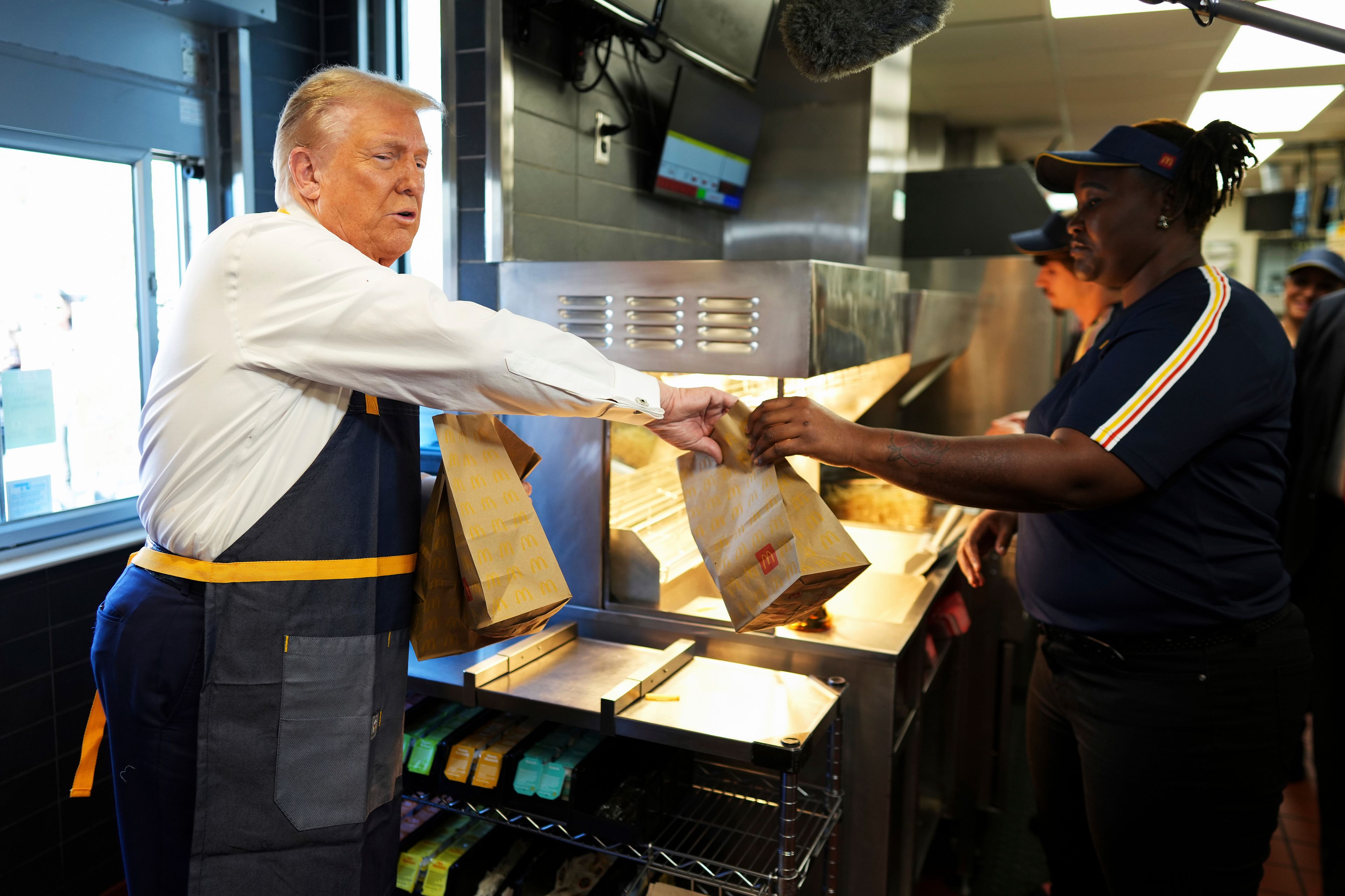 An employee hands an order to Republican presidential nominee former President Donald Trump during a visit to McDonald's in Feasterville-Trevose, Pa., Sunday, Oct. 20, 2024. (Doug Mills/The New York Times via AP, Pool)