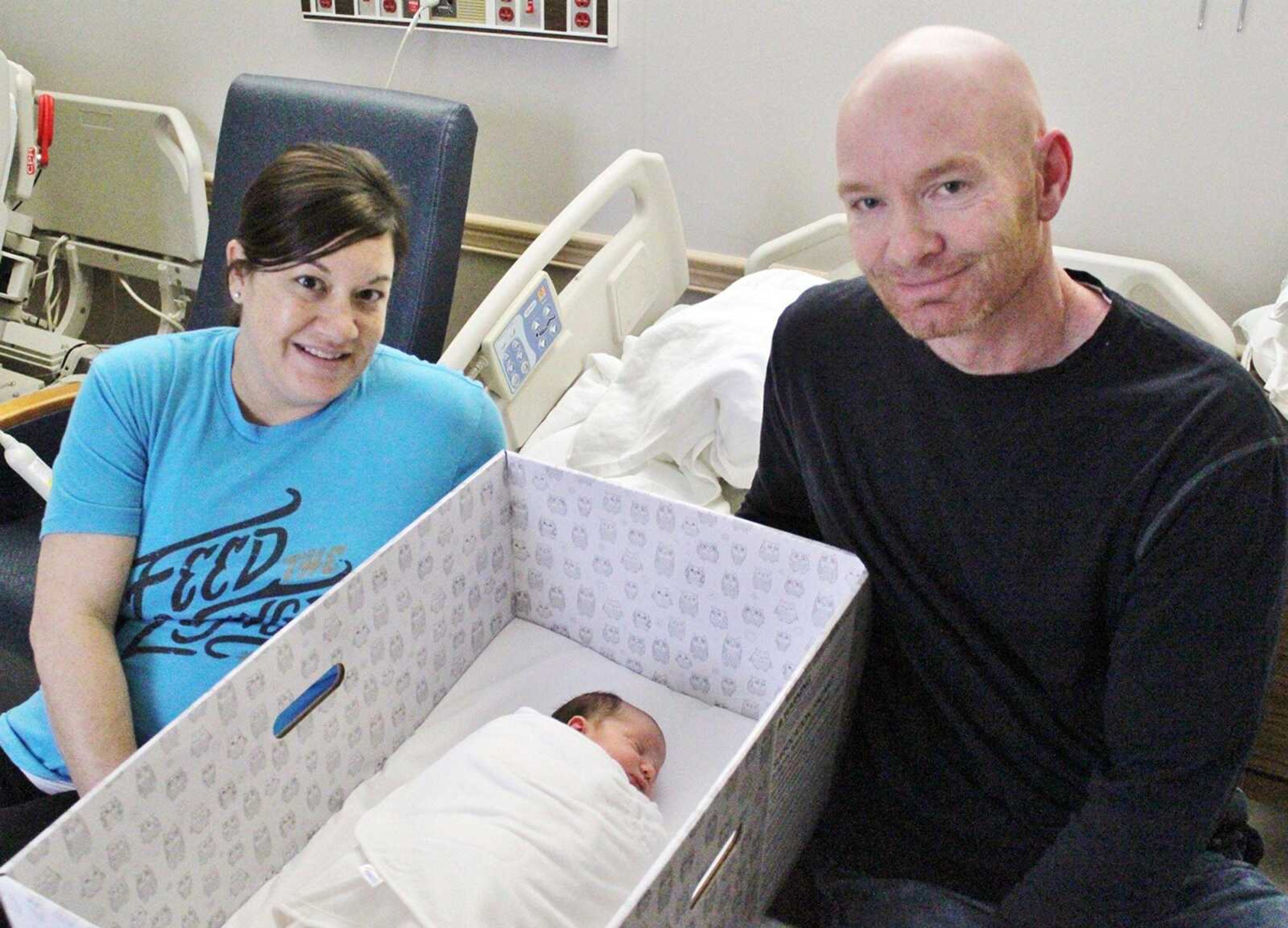 Tessa and Cliff Jackson of Sikeston, Missouri, pose with their infant daughter in one of the boxinettes distributed by three area hospitals. The boxinette is designed to prevent accidental sleeping deaths. Tessa Jackson noted of the box: "I can see where it would be useful for traveling."