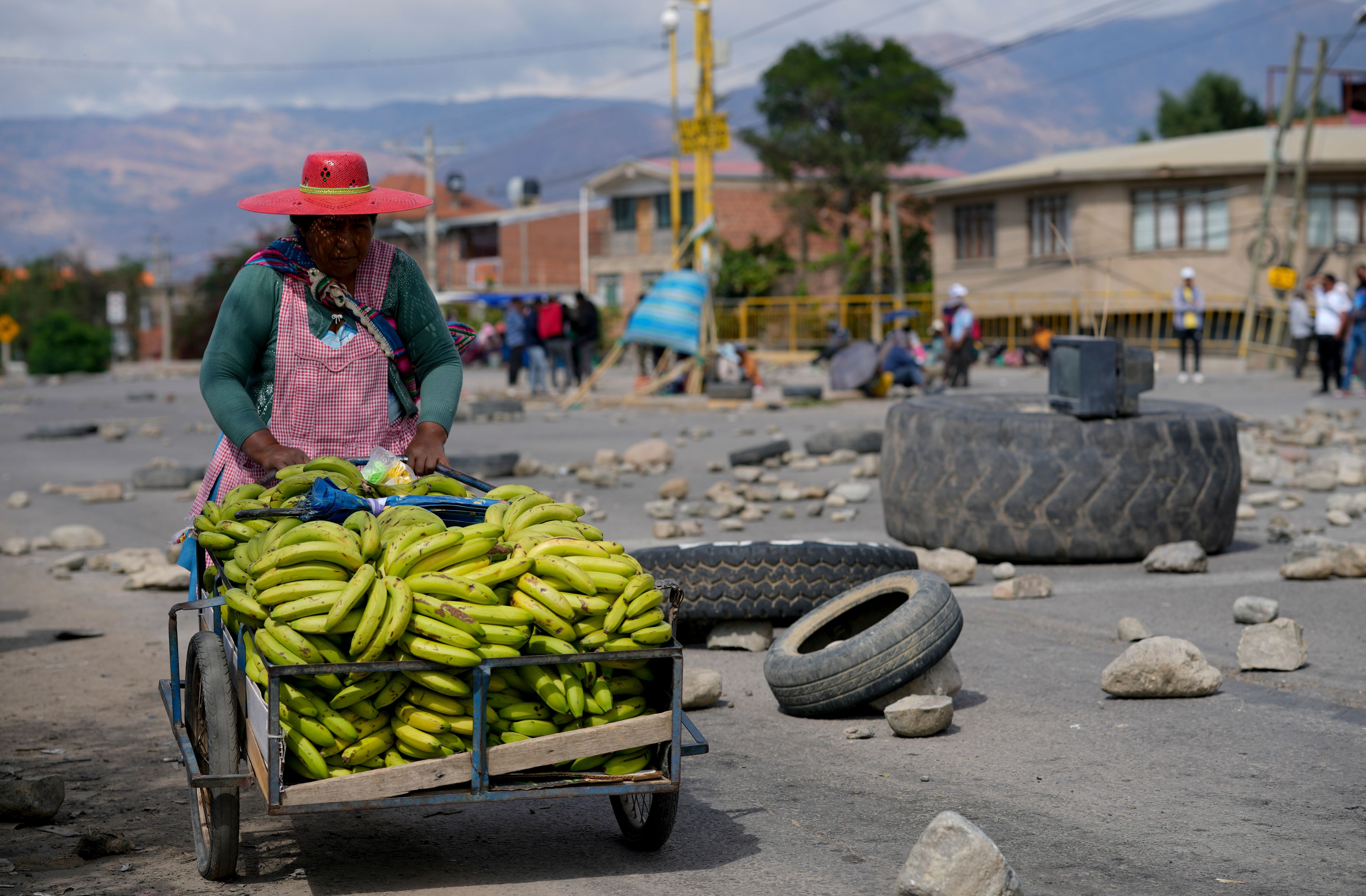 A woman pushes a banana cart as supporters of Bolivian former President Evo Morales block roads to prevent him from facing a criminal investigation over allegations of abuse of a minor and to demonstrate against an alleged assassination attempt, near Cochabamba, Bolivia, Monday, Oct. 28, 2024. (AP Photo/Juan Karita)