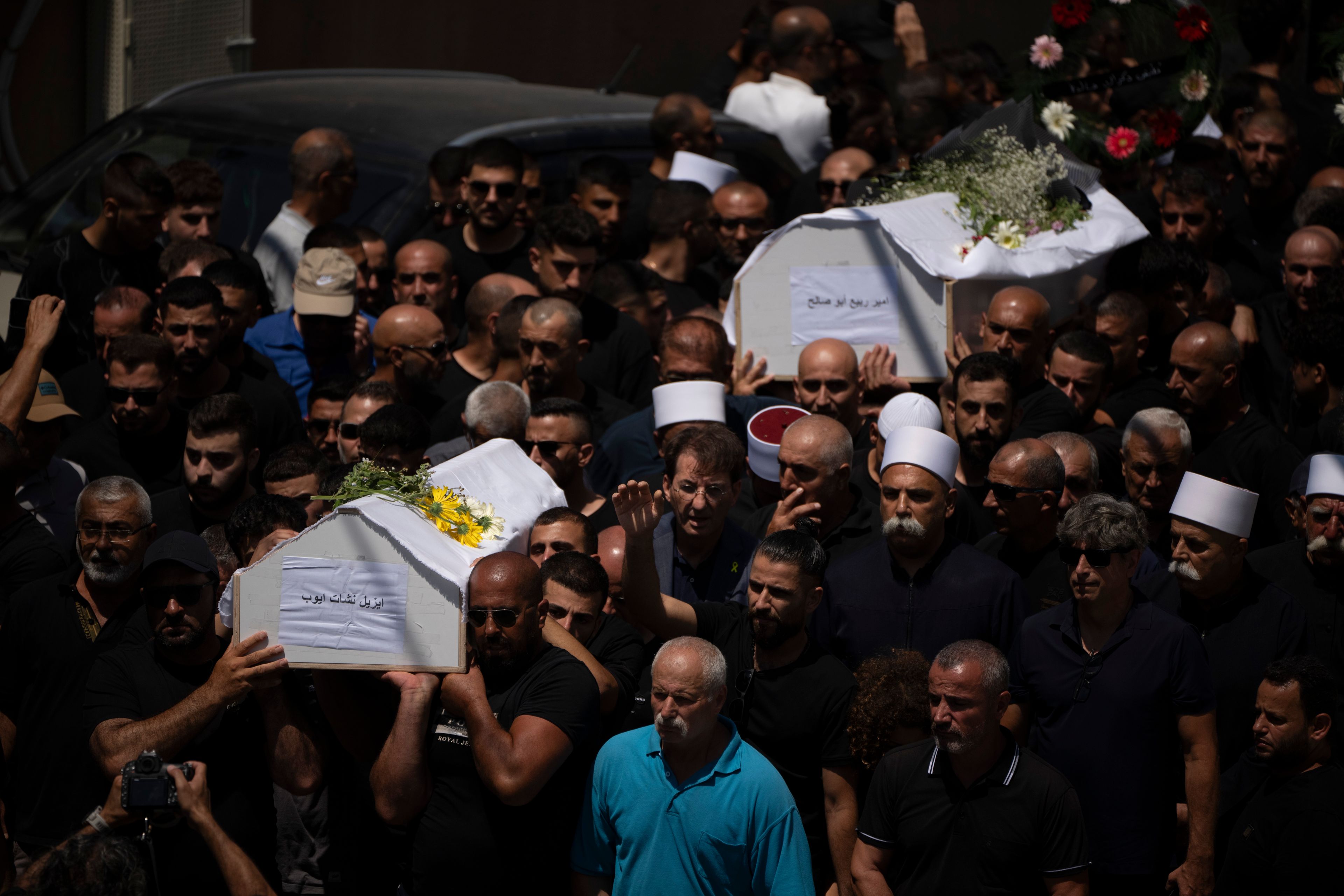 Mourners from the Druze minority carry the coffins of some of the 12 children and teens killed in a rocket strike at a soccer field during their funeral, in the village of Majdal Shams, in the Israeli-annexed Golan Heights, Sunday, July 28, 2024. It's the deadliest strike on an Israeli target along the country's northern border since the fighting between Israel and the Lebanese militant group Hezbollah began. (AP Photo/Leo Correa)