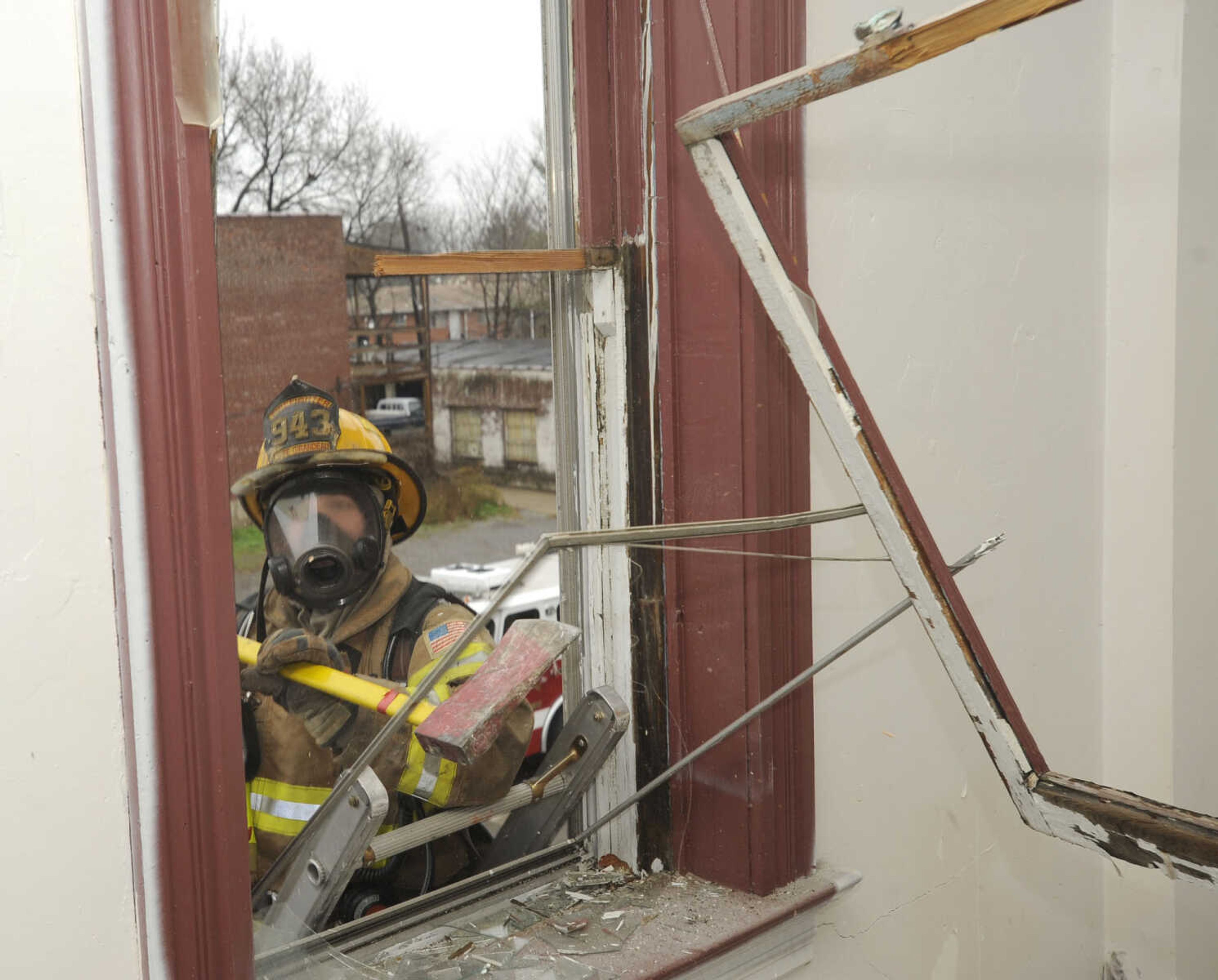 Firefighter Sam Jenne smashes the window frame before entering the building.