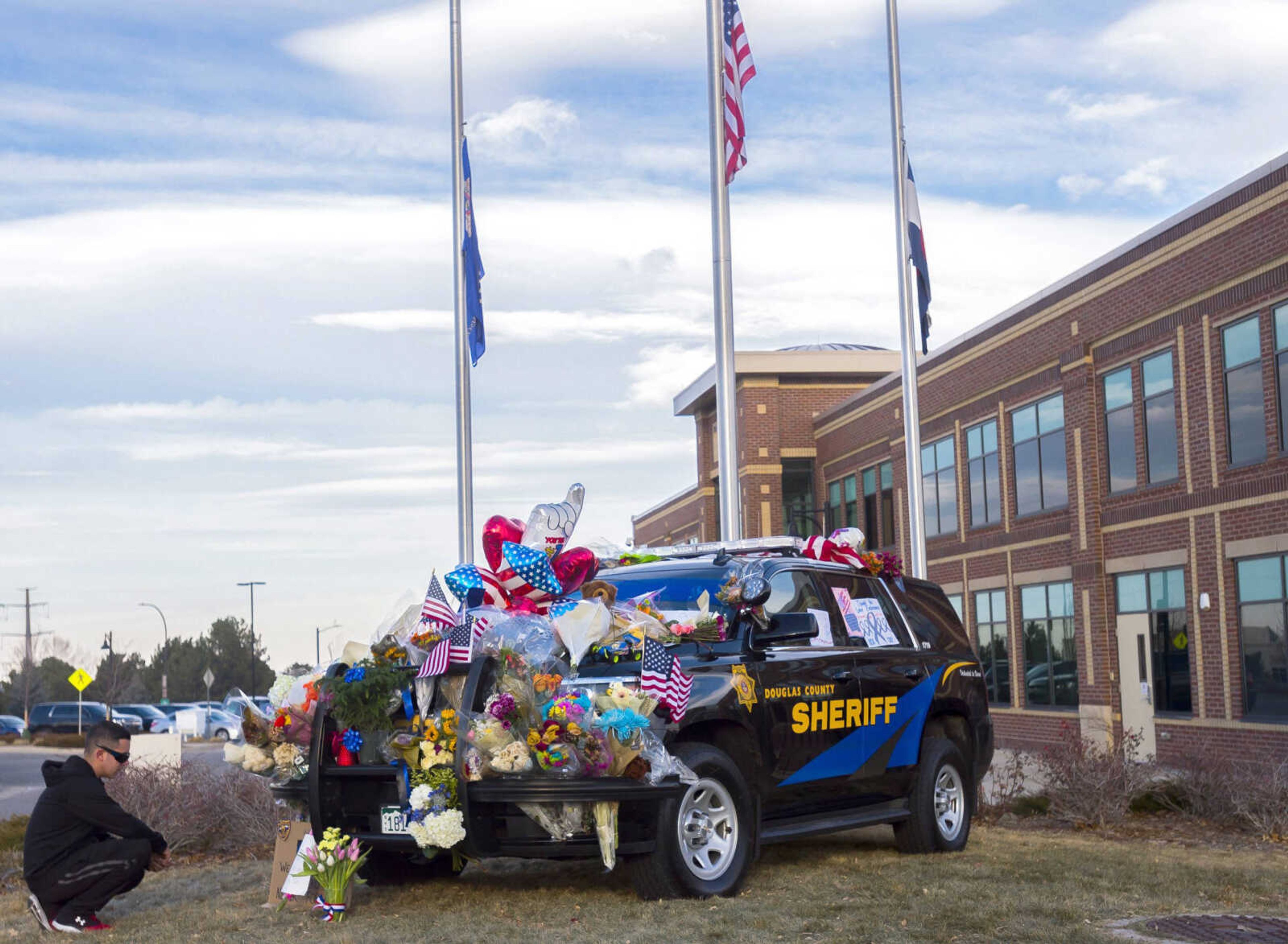 Jesus Olivas takes a moment to look at a police cruiser that served as a makeshift memorial for deputy Zackari Parrish, 29, on Monday at the Douglas Country Sheriff Substation in Highlands Ranch, Colorado.