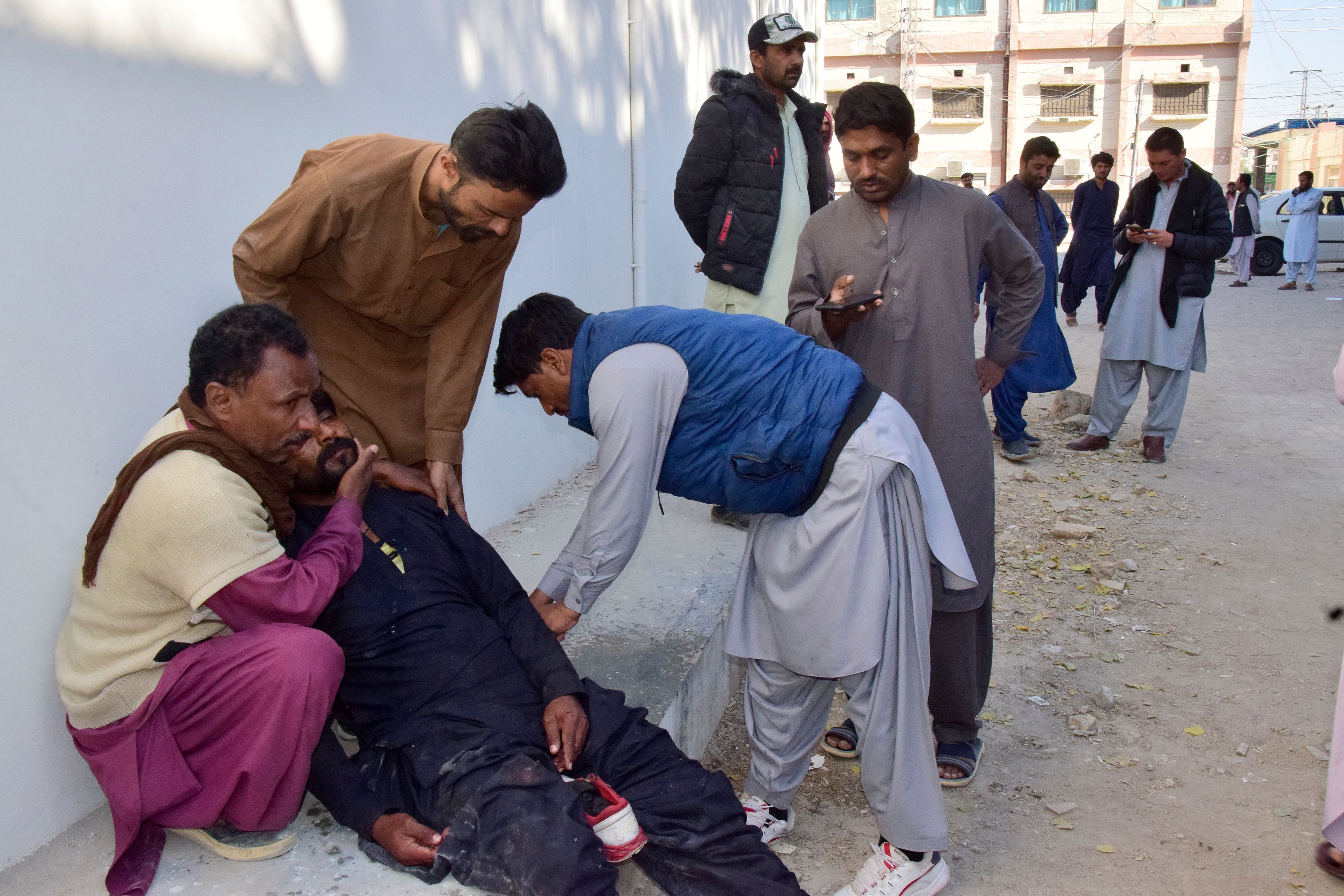 People comfort a man, who mourns over the death of his family member in a bomb explosion at railway station, outside a hospital in Quetta, southwestern Pakistan, Saturday, Nov. 9, 2024. (AP Photo/Arshad Butt)