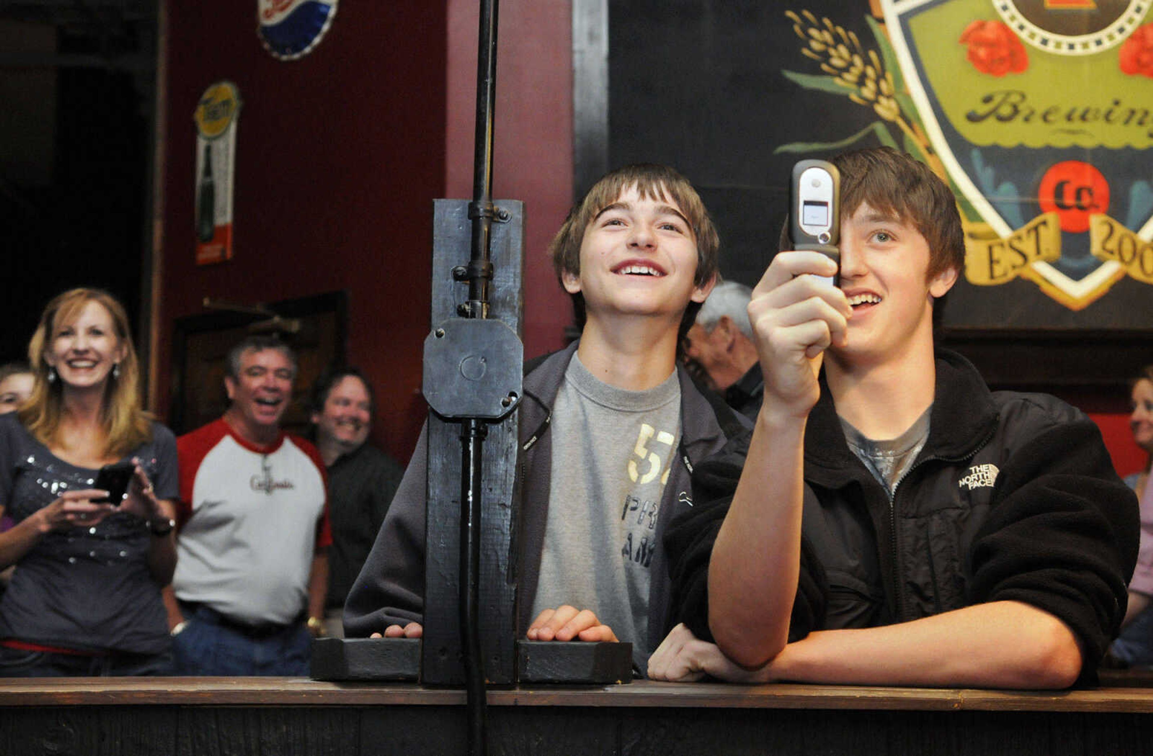 KRISTIN EBERTS ~ keberts@semissourian.com

Creighton Miles, 12, left, and Eli Seger, 14, watch and take photos as Eli's father Dan Seger, of the Cape Girardeau Police Department, gets his head shaved during the St. Baldrick's event at Buckner Brewing Company in Cape Girardeau, Mo., on Saturday, April 24, 2010. The twenty-five area participants in the event raised over $9,000 collectively before shaving their heads in front of family and friends to benefit the St. Baldrick's Foundation for child cancer research.