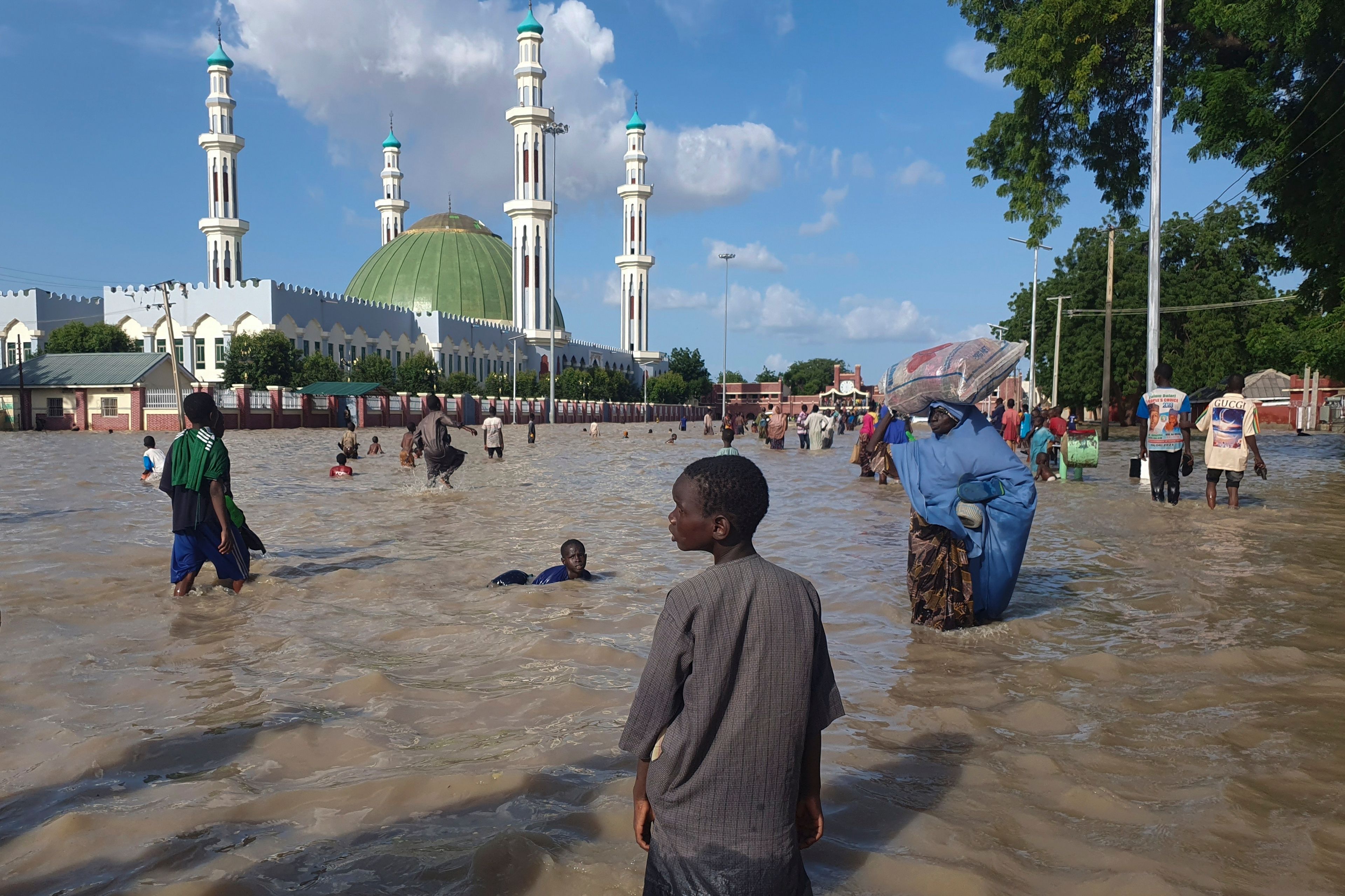 FILE - People walk through floodwaters following a dam collapse in Maiduguri, Nigeria, Tuesday, Sept 10, 2024. (AP Photos/ Joshua Olatunji, File)