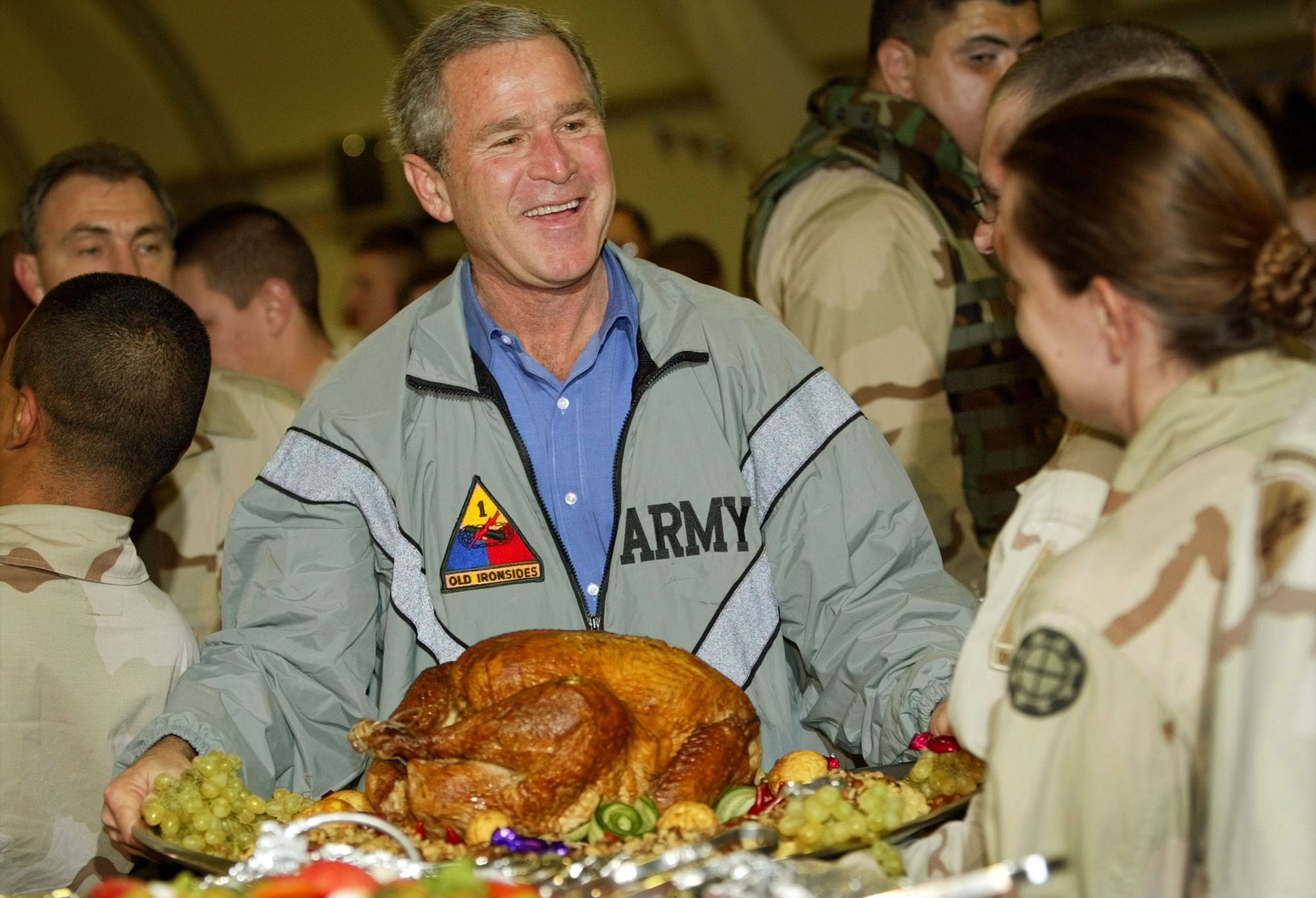 The Nov. 27, 2003 file photo shows President George W. Bush, center, holding up a turkey platter for U.S. troops at Baghdad International Airport in Baghdad, Iraq. Bush paid a surprise Thanksgiving day visit to American troops in Baghdad, flying to Baghdad from his ranch in Crawford, Texas, to visit U.S. troops station in Iraq for Thanksgiving holiday. 