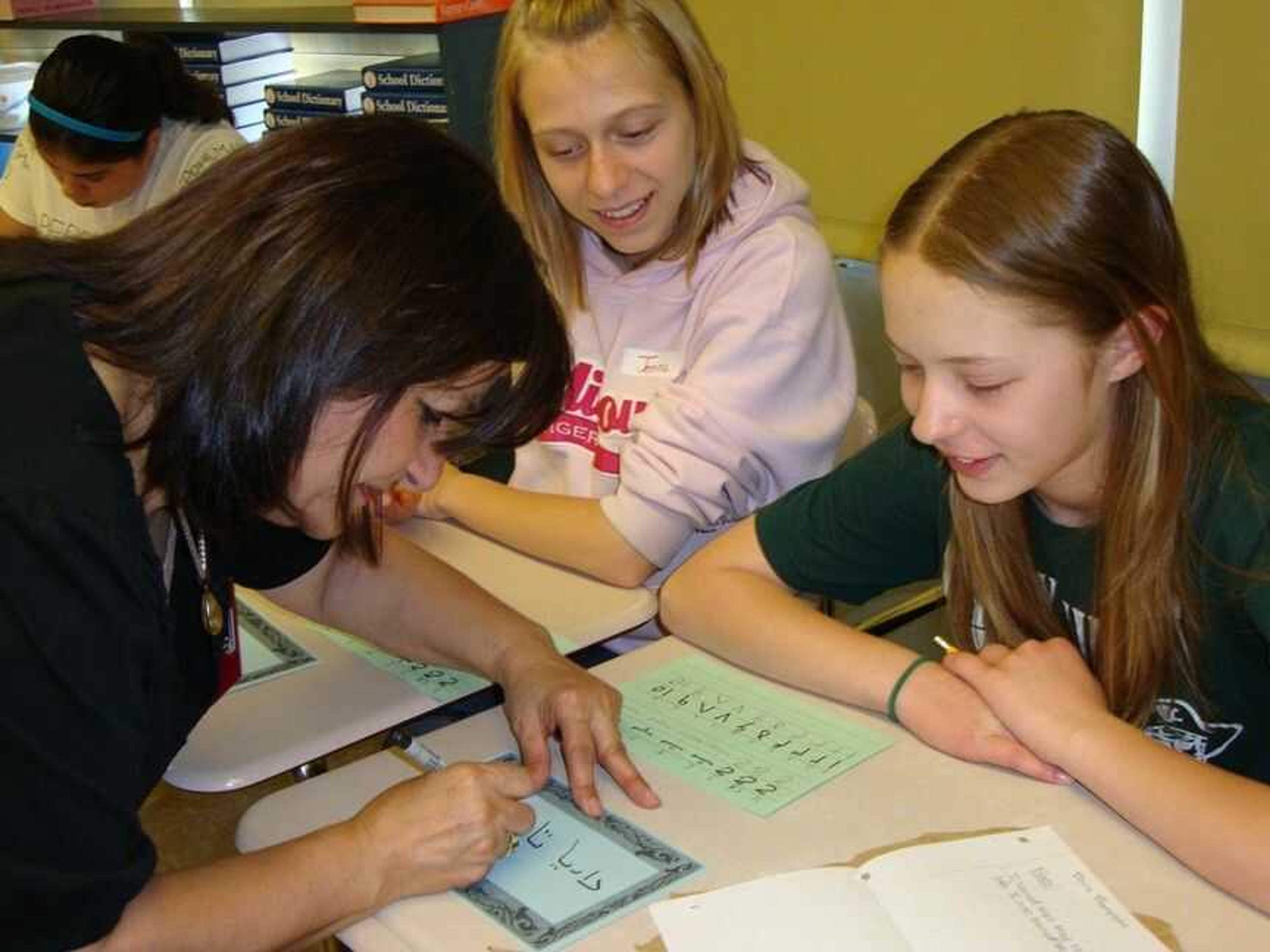 Dr. Simin Cwick shows Jenna LaRose (left) and Daria Thompson how to write their names in Farsi script. (Photo by Perry County School Dist. No. 32)