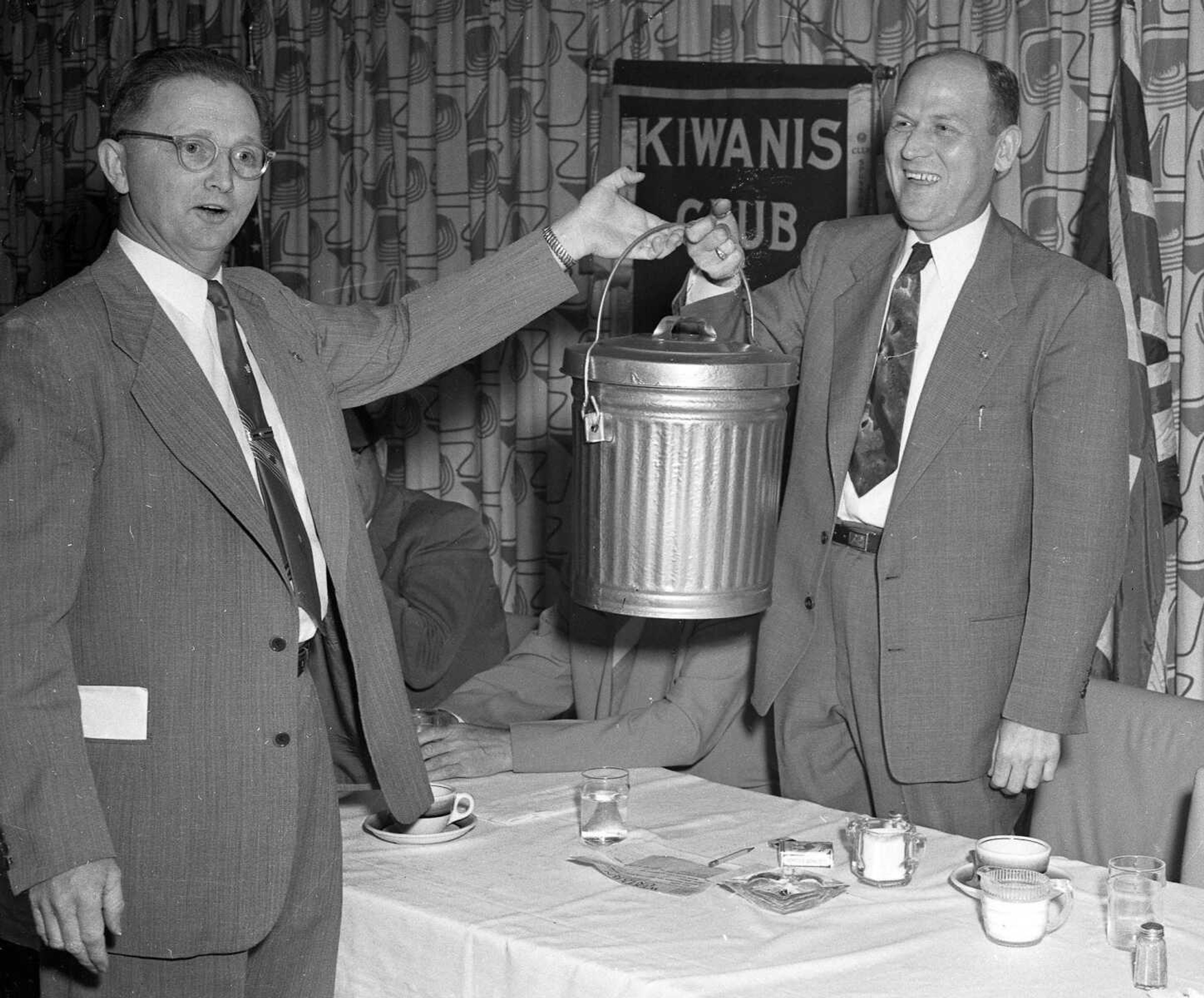 May 18, 1954 Southeast Missourian. Members of the Kiwanis Club decided to call attention of one of its members, recently-elected Mayor Narvol A. Randol, at right, to problems of his office by presenting him with a new disposal pail laden with "greenbacks." The "greenbacks" were of the stage variety which members "contributed" as the pail was passed among those attending last week's meeting. The presentation was made by Carlton Lorberg. [Carlton Lorberg operated Lorberg Funeral Home and Lorberg Appliance, both located on South Sprigg.] (G.D. Fronabarger/Southeast Missourian archive)