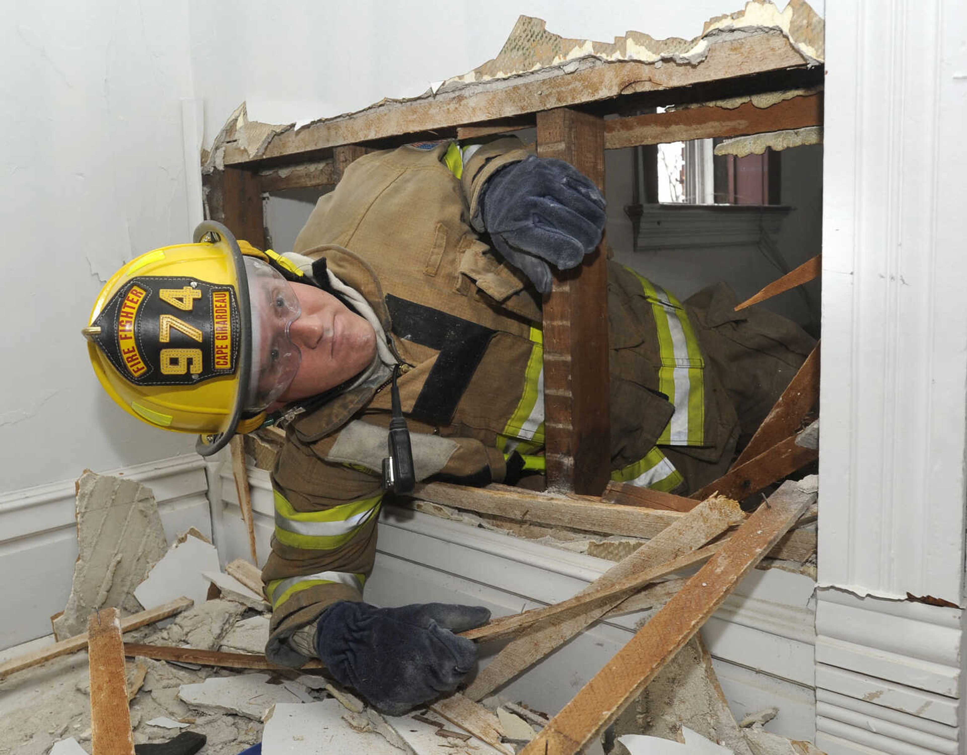 Firefighter Bryan Stroer simulates a self-rescue through a hole chopped through a wall.