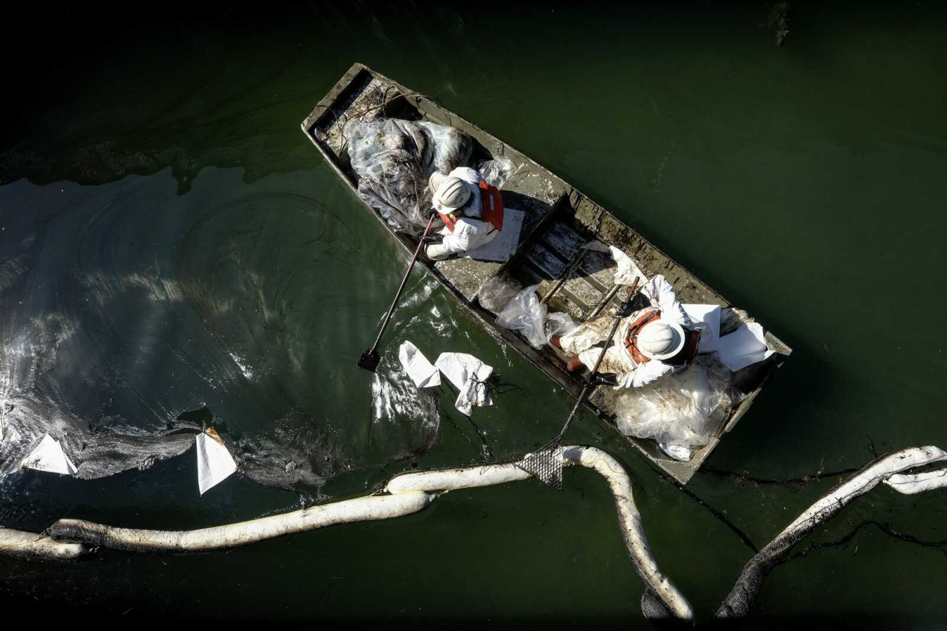 Workers in protective suits clean oil Tuesday in an inlet leading to the Wetlands Talbert Marsh after an oil spill in Huntington Beach, California.