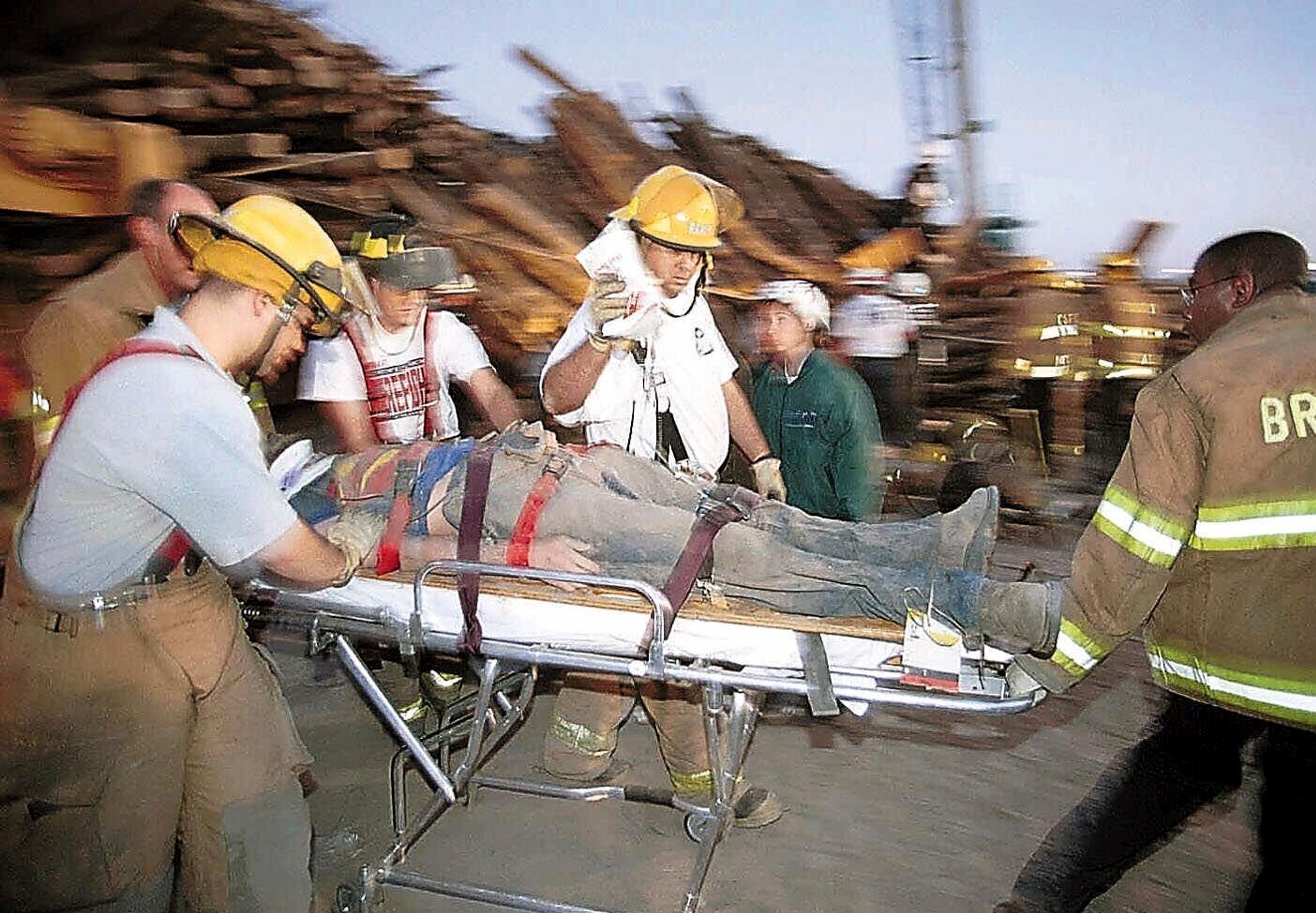 FILE - Emergency workers rush a student who was trapped for hours under a stack of logs which collapsed while being prepared for a pre-football game bonfire, Nov. 18, 1999, at Texas A&M University in College Station, Texas. (Dave McDermand/College Station Eagle via AP, File)