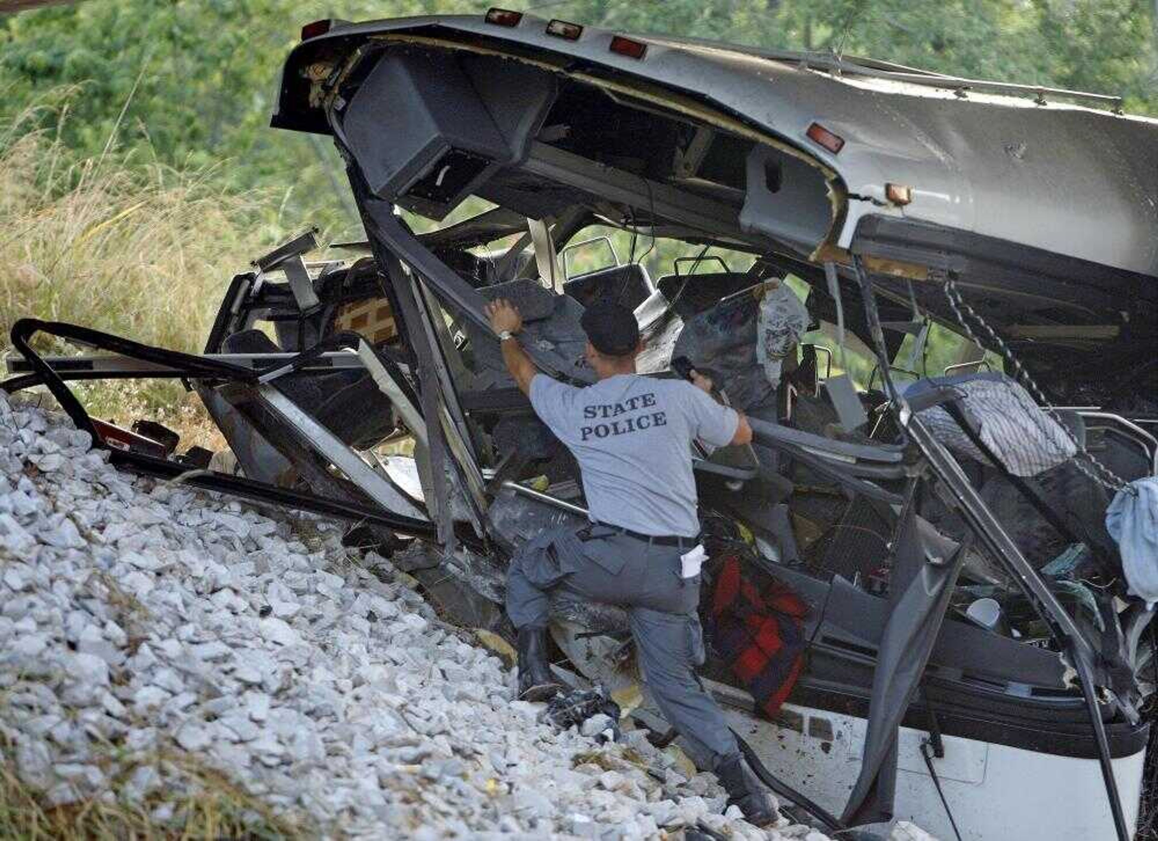 Kentucky State Trooper Terry Alexander inspected the wreckage of a tour bus Monday on Interstate 65 near Smiths Grove, Ky. One person was killed and 66 were injured in the crash. The chartered bus carrying family members home from a family reunion in New York was returning to Alabama when it left the road and crashed near an overpass on I-65. (John Russell ~ Associated Press)