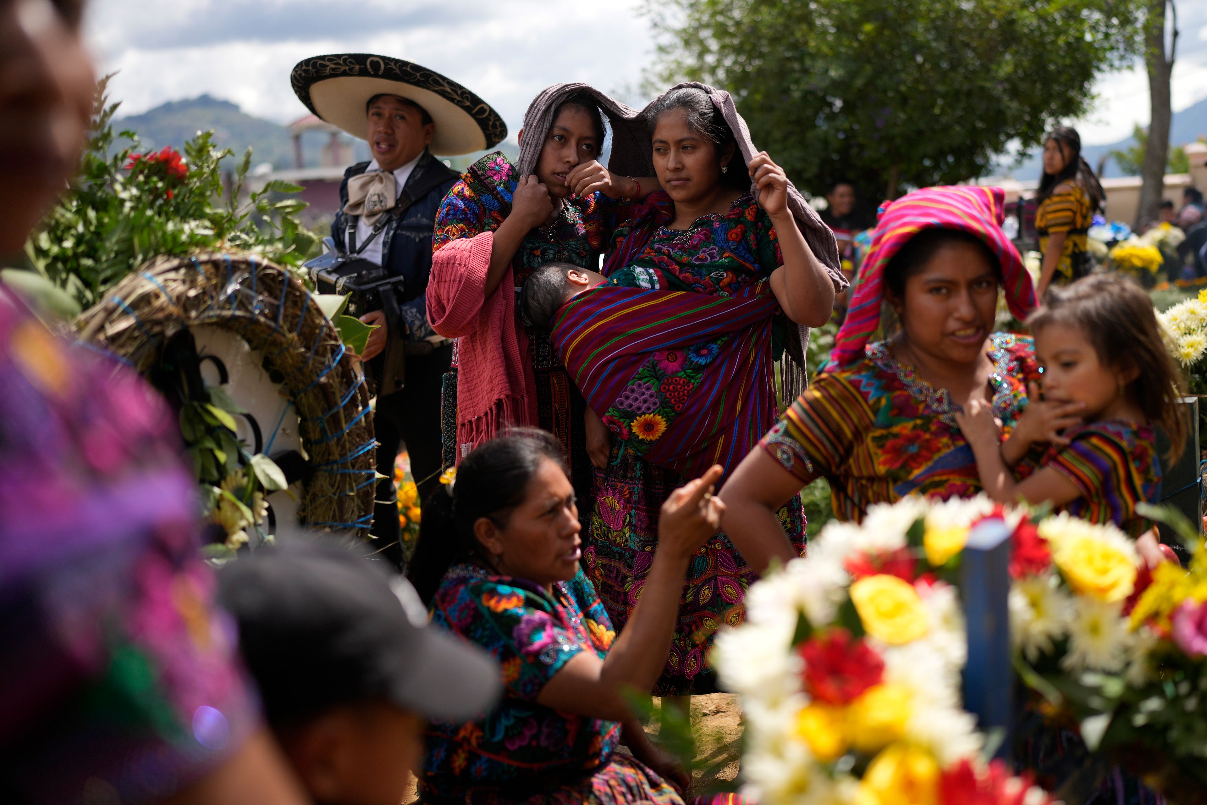 Family members visit the grave of a relative during All Saints Day celebrations at the cemetery of Sumpango, Guatemala, Friday, Nov. 1, 2024, as part of Day of the Dead celebrations. (AP Photo/Matias Delacroix)