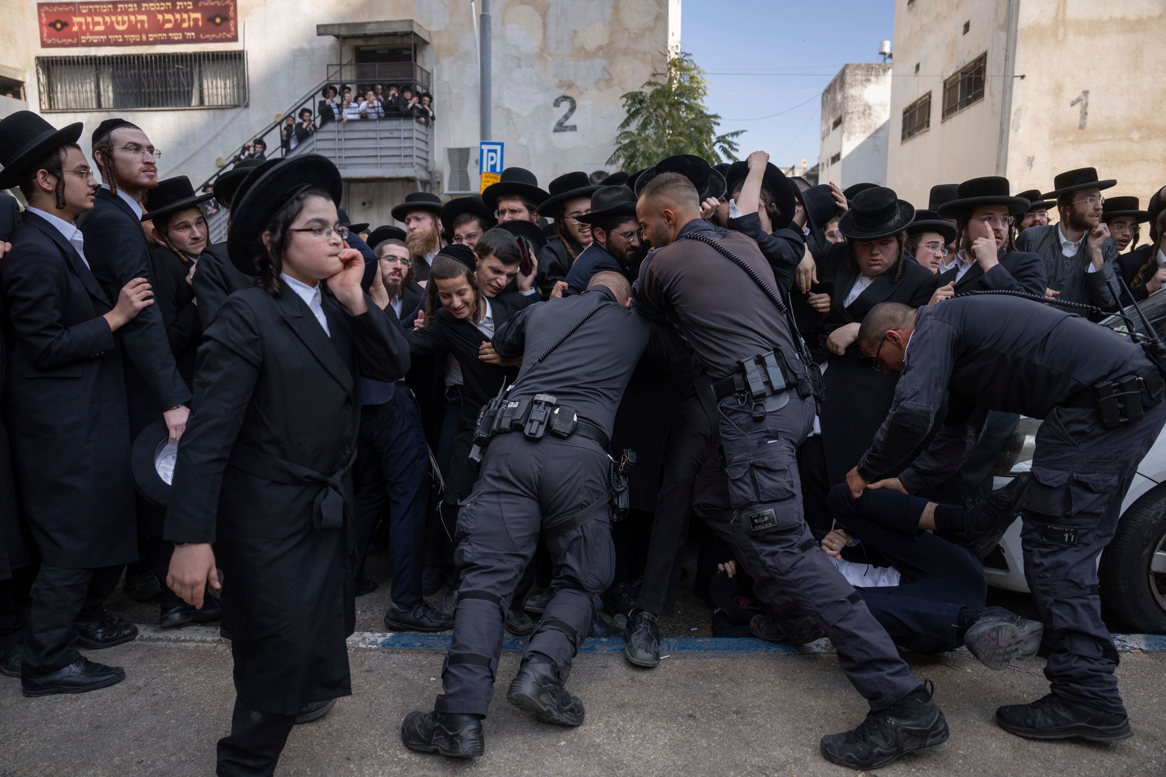 Israeli police officers scuffle with ultra-Orthodox Jewish men during a protest against a potential new draft law which could end their exemptions from military service in Jerusalem, Thursday, Oct. 31, 2024. (AP Photo/Ohad Zwigenberg)