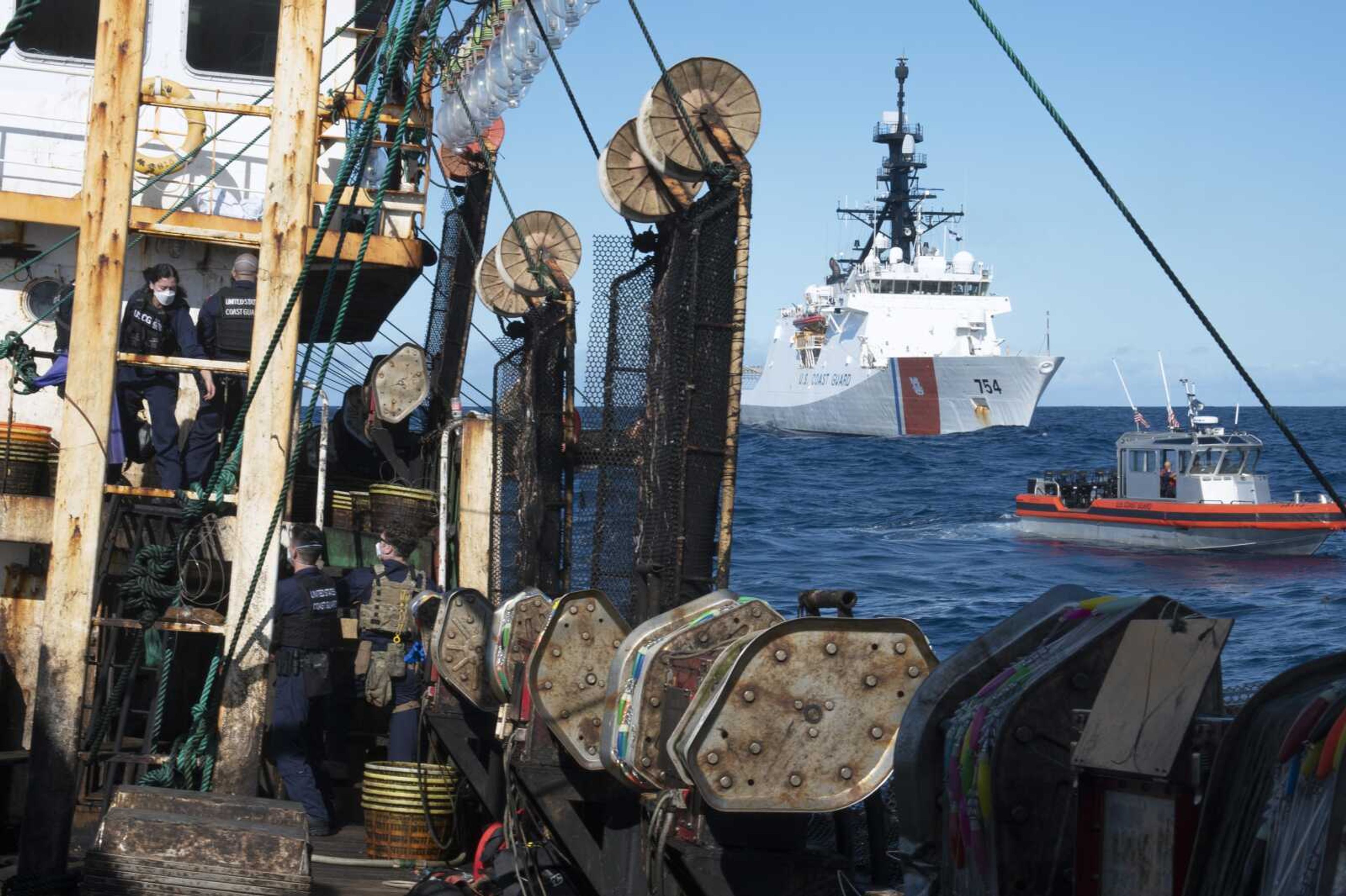 Guardsmen from the cutter James, seen at background right, conduct a boarding of a fishing vessel Aug. 4 in the eastern Pacific Ocean. During the 10-day patrol for illegal, unreported or unregulated fishing, three vessels steamed away. Another turned aggressively 90 degrees toward the James, forcing the American vessel to maneuver to avoid being rammed.