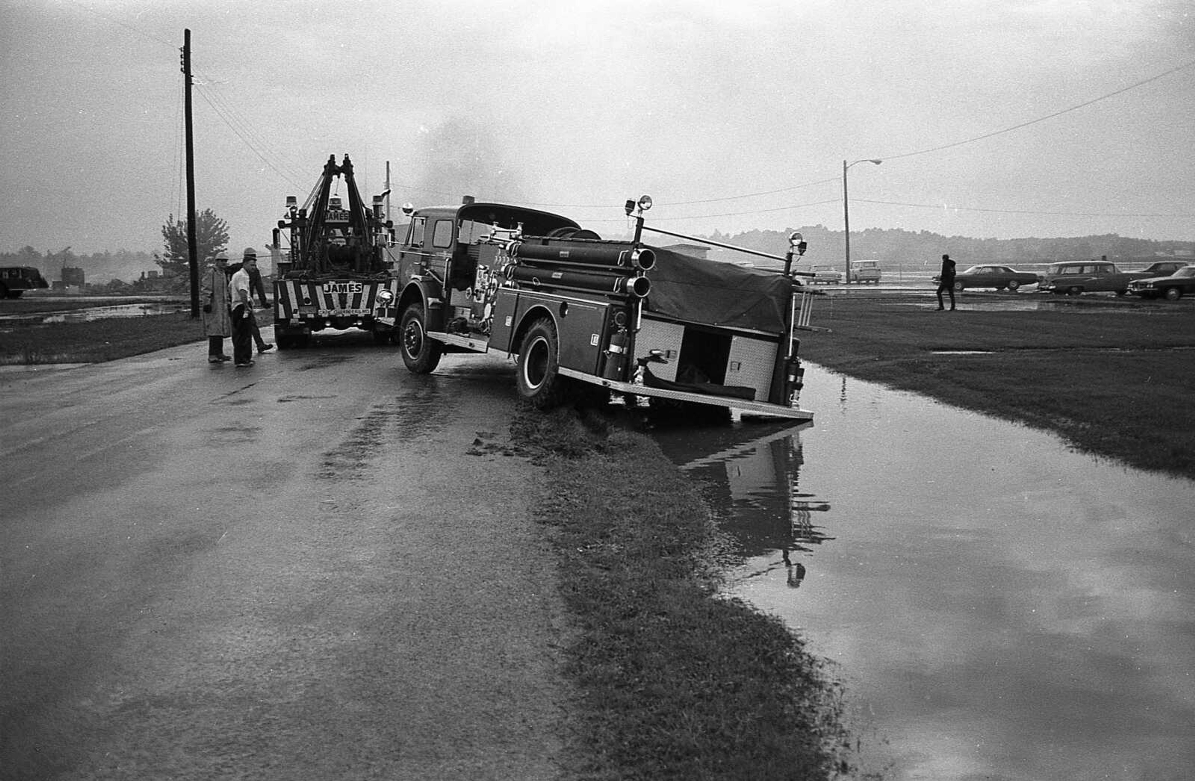 Published July 15, 1971.
Workers prepare to pull the city's pumper from a ditch into which it ran en route to the fire. Water across he roadway made it impossible for the driver to see. (Southeast Missourian archive)