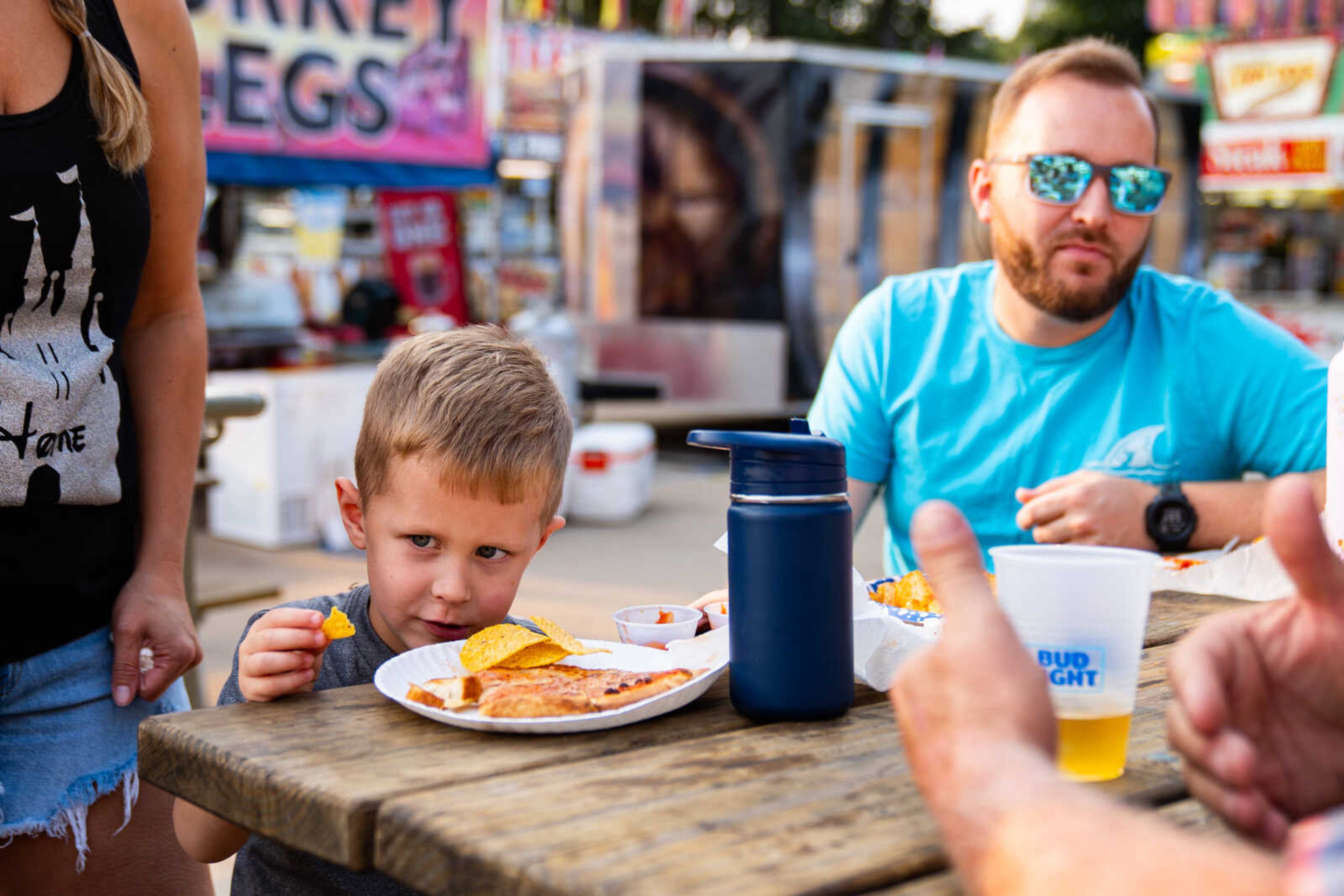 Maddox Smith, center, enjoys some fair food with his father, Michael Smith.