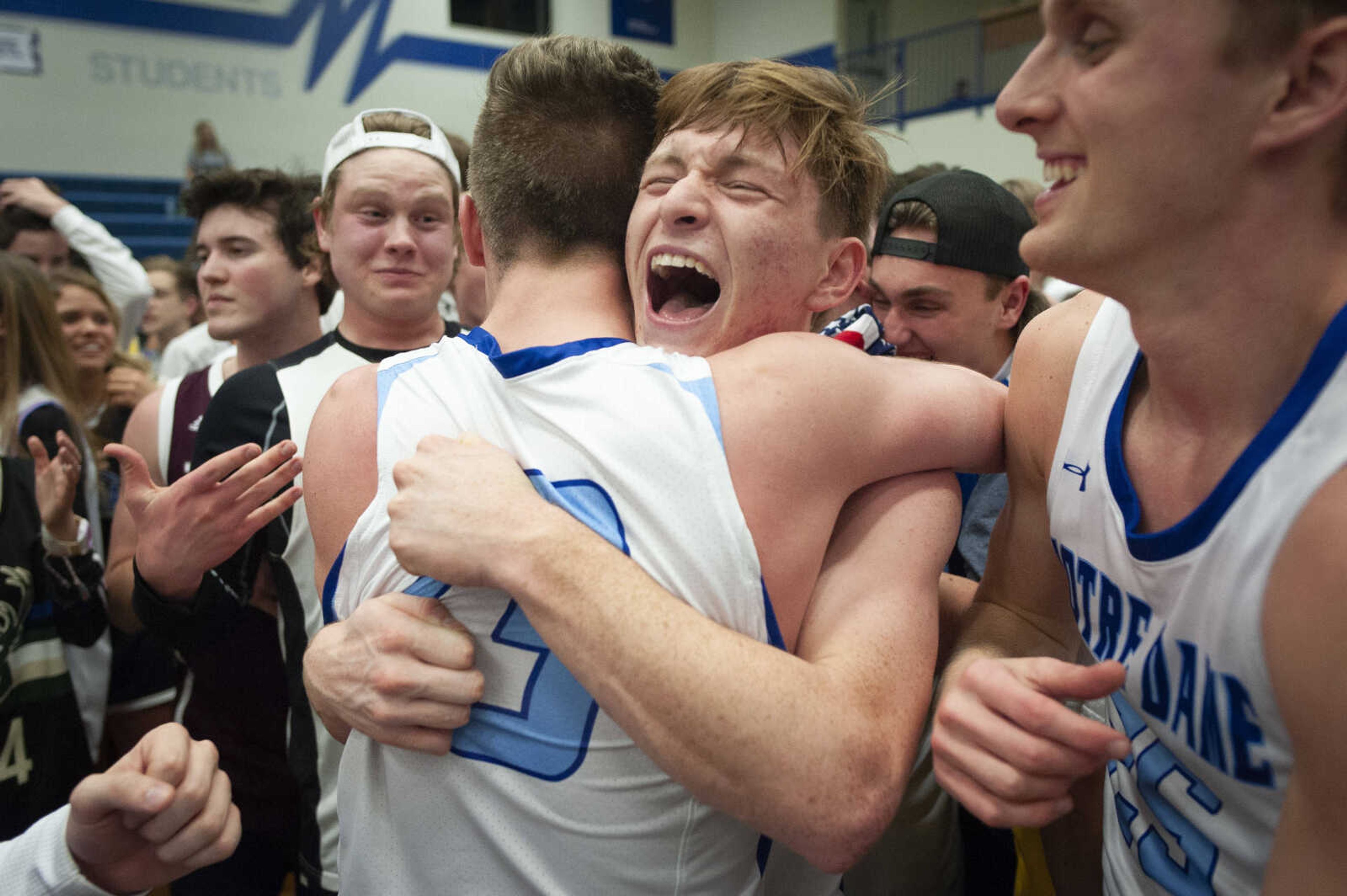 Notre Dame senior Kam Dohogne (11), facing forward, hugs teammate senior Jack Floyd (13) near teammate senior Tyler Parker (25) following the Notre Dame Bulldogs' 38-37 double-overtime win against the Cape Central Tigers in the Class 4 District 1 championship Friday, March 6, 2020, at Notre Dame Regional High School in Cape Girardeau.